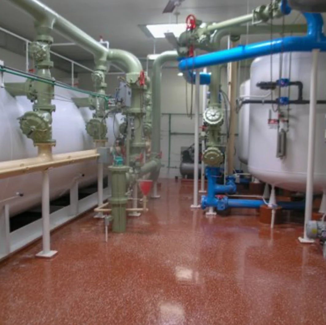 Industrial mechanical room with large pipes, valves, and gauges.