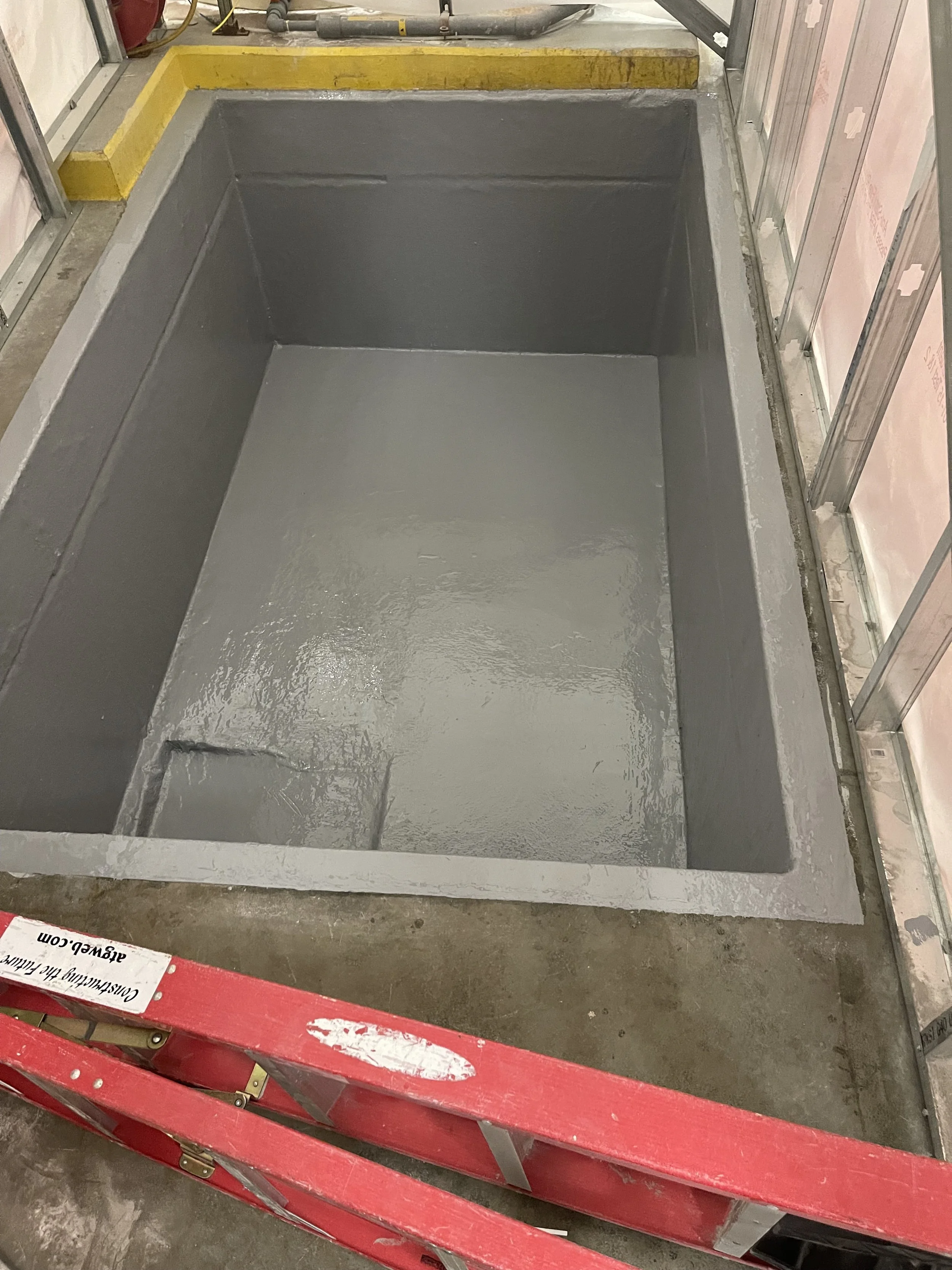 A newly coated waterproof basement or crawl space with a smooth gray epoxy finish.