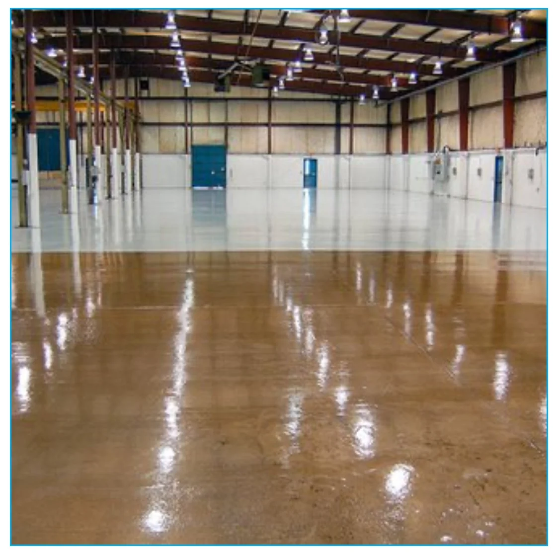 Interior of an empty warehouse with polished wooden and white concrete floors, high ceiling with exposed beams and hanging lights, and blue doors along the back wall.