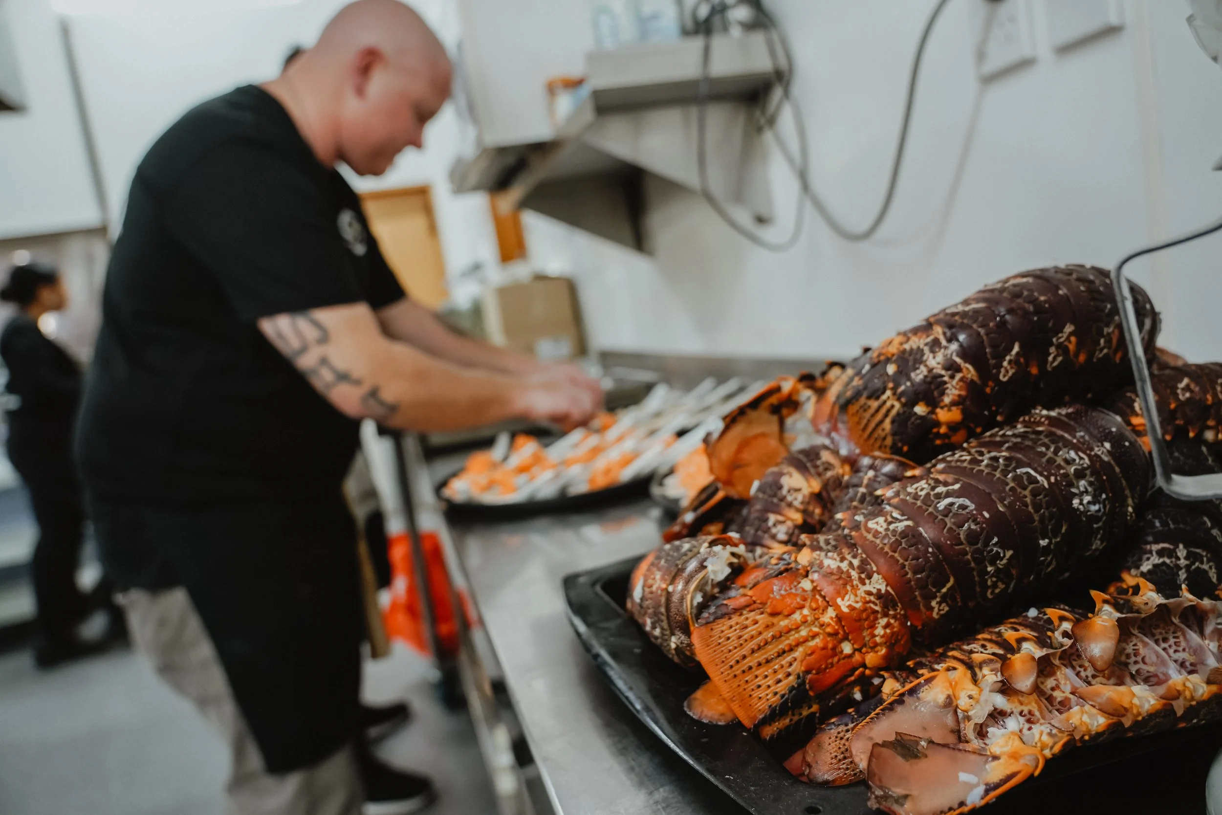 A man preparing cooked lobster on a counter in a kitchen or kitchen-like setting.