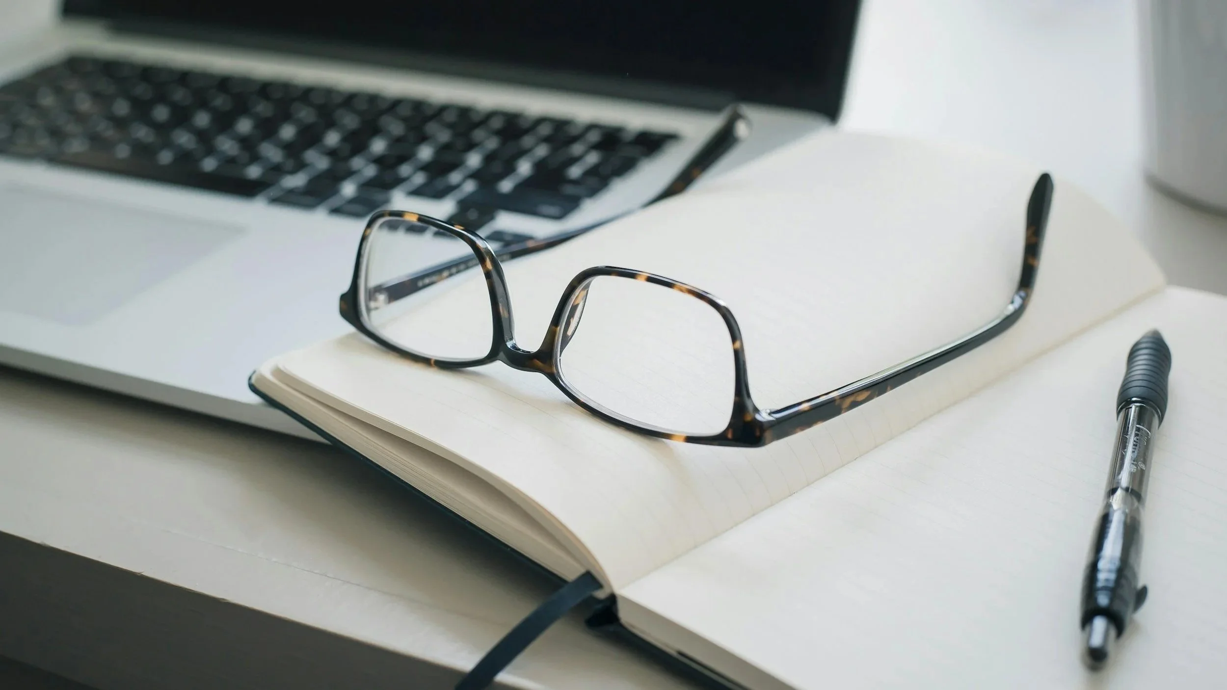 A professional notebook and reading glasses on a desk, symbolizing the strategic planning and institutional reflection required in modern legal practice.