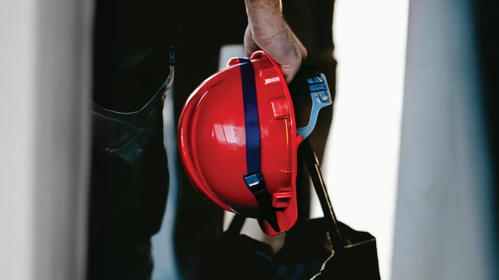 A close-up shot of a hand holding a hard hat, symbolizing the readiness, safety, and personal commitment required to build a career in construction leadership.