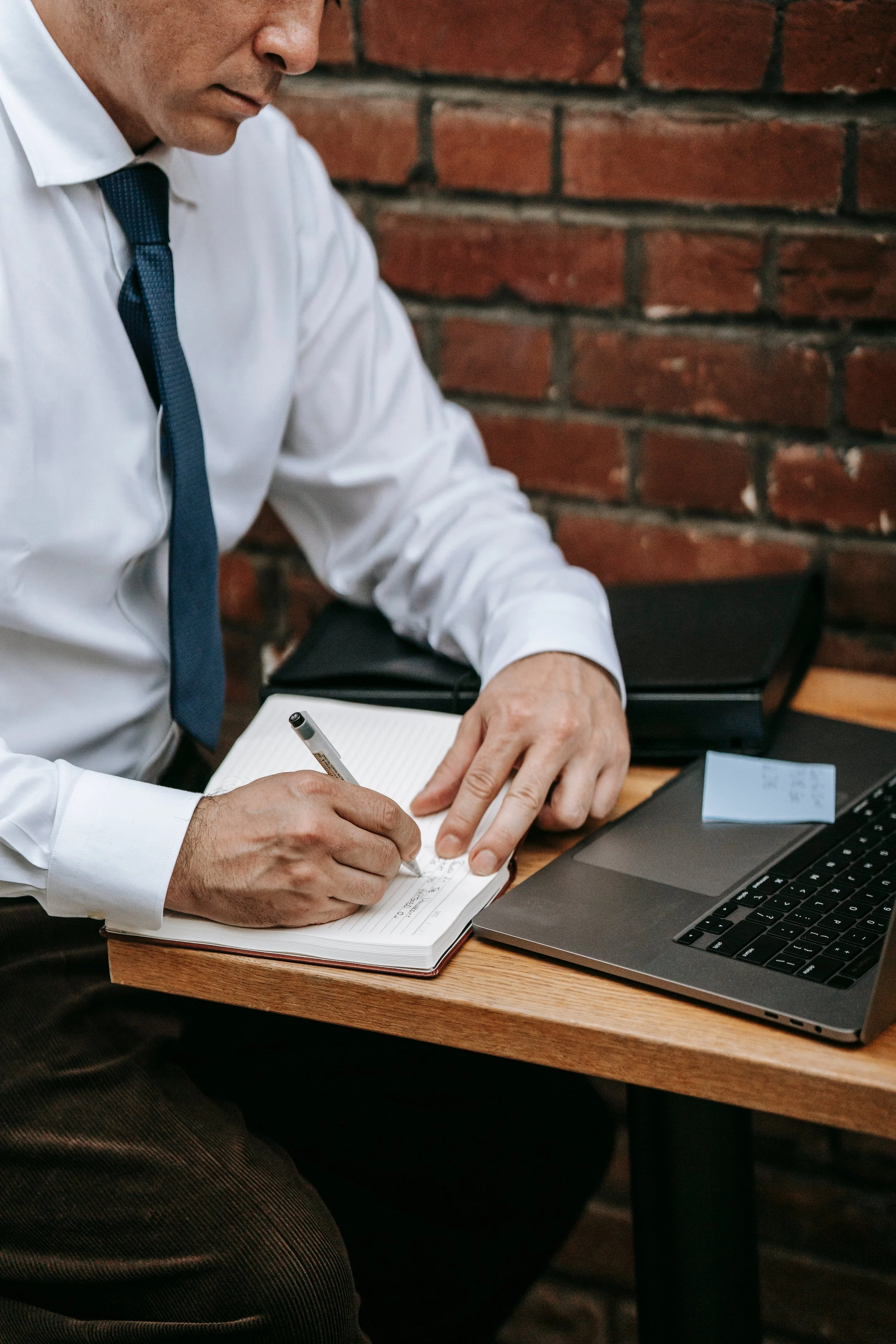 Person writing in a notebook at a desk in Atlanta, Georgia, representing focused work and planning.