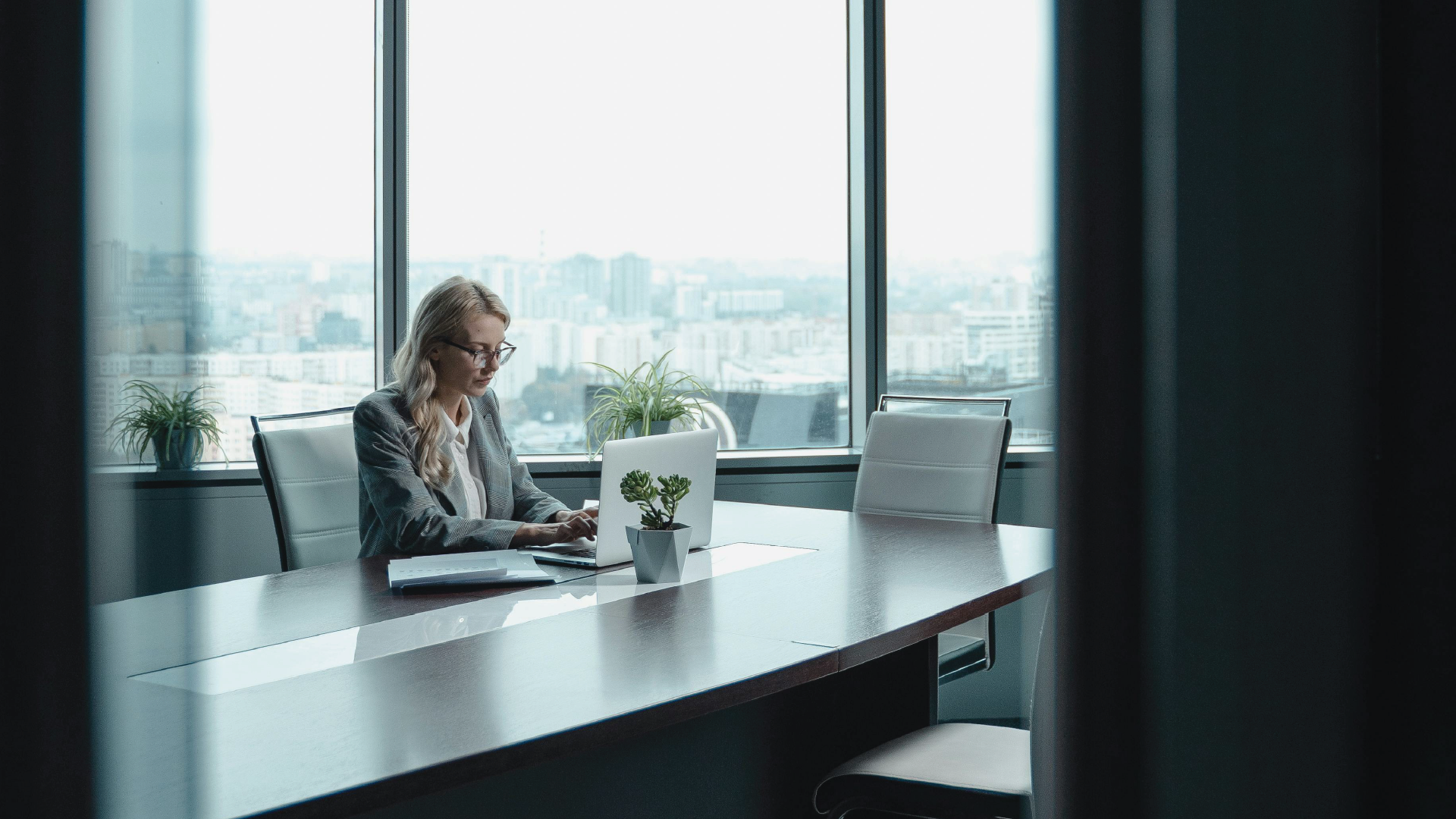 A professional woman leading a discussion at a conference table, representing the role of personal influence and leadership in the modern business economy.