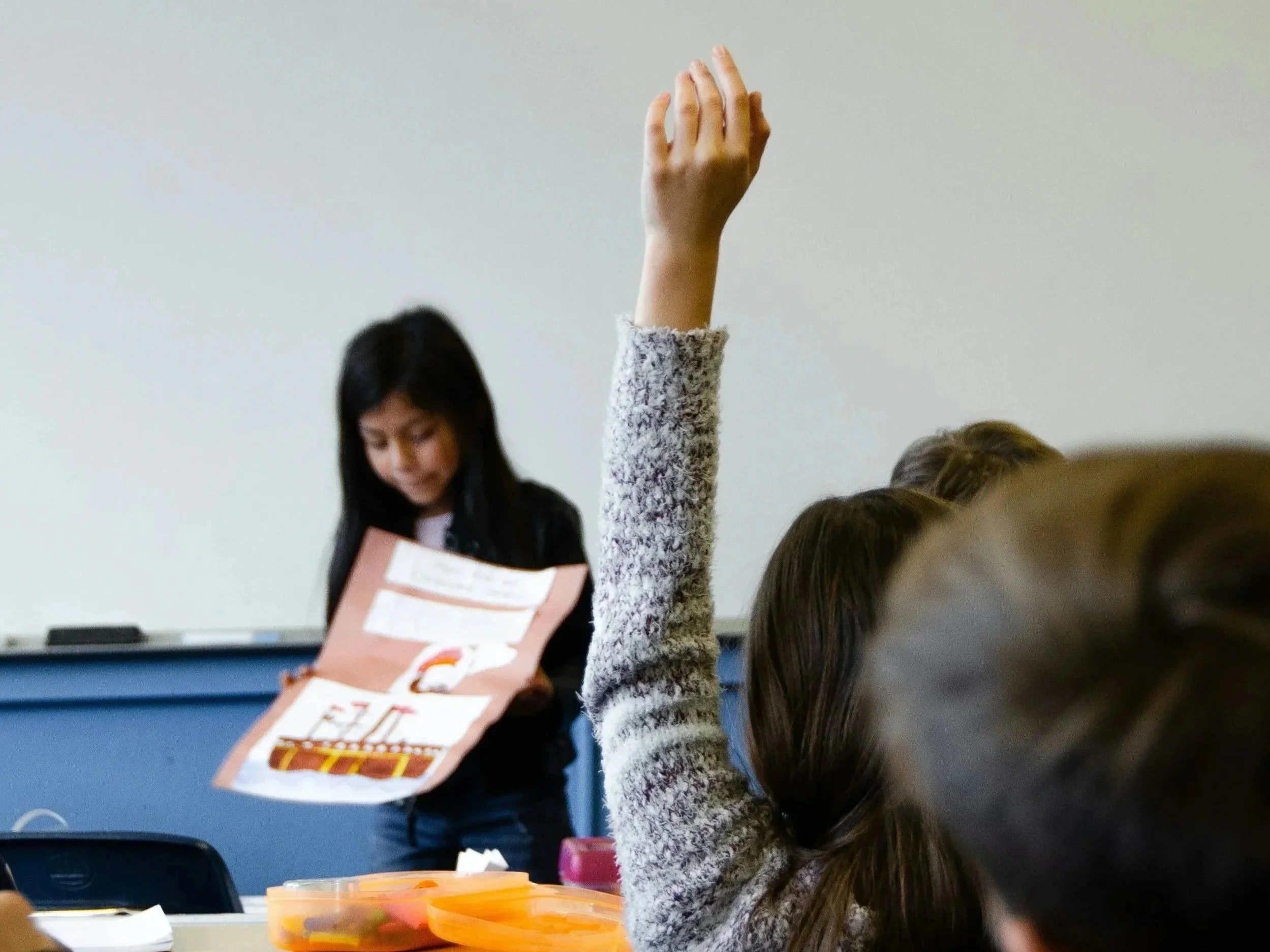 An intelligent girl raises her hand. She may be in need of testing for giftedness.