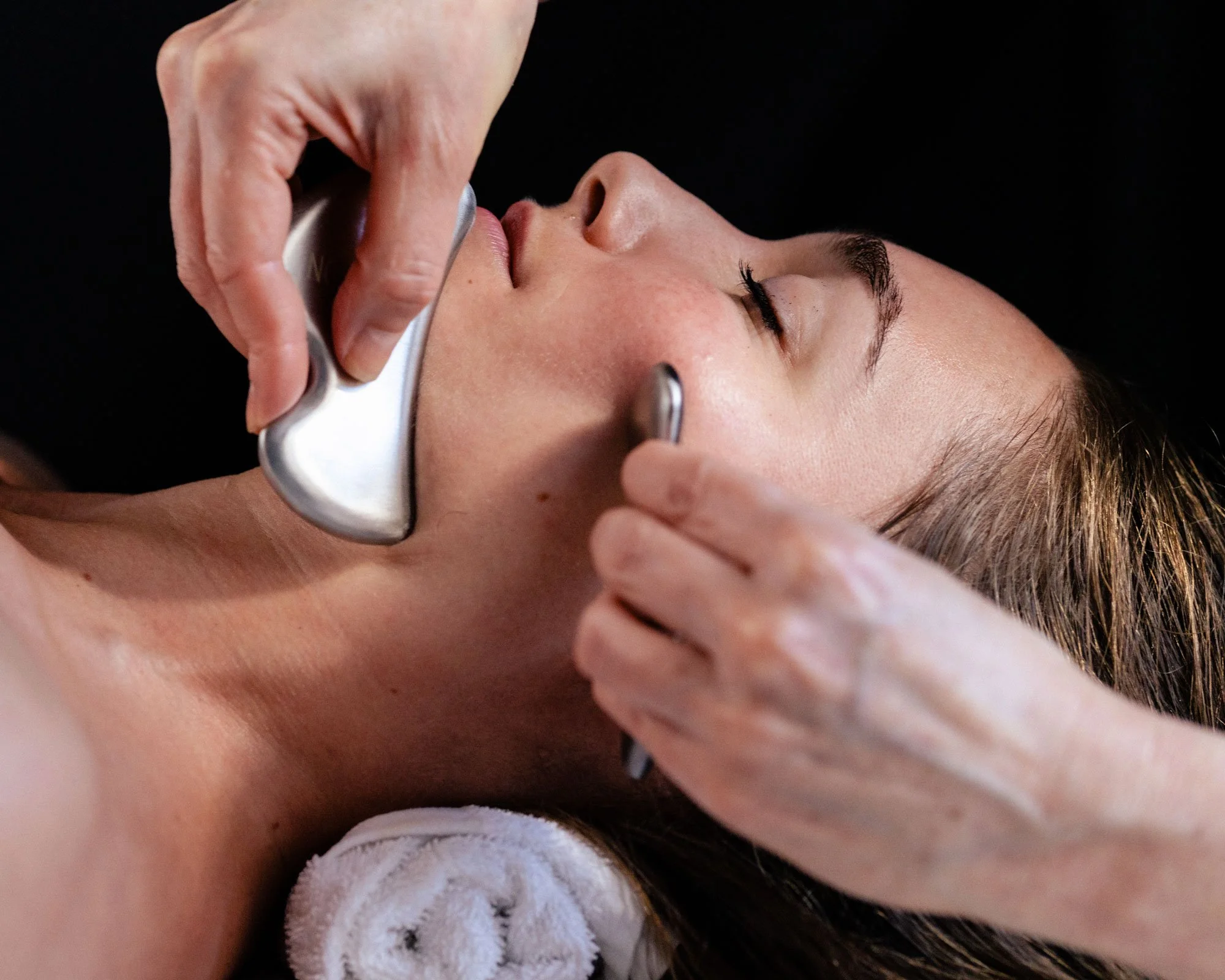 Close up of a women's face being massaged with silver rollers by an esthetician,, receiving an Anti-Aging facial treatment at Knot Springs