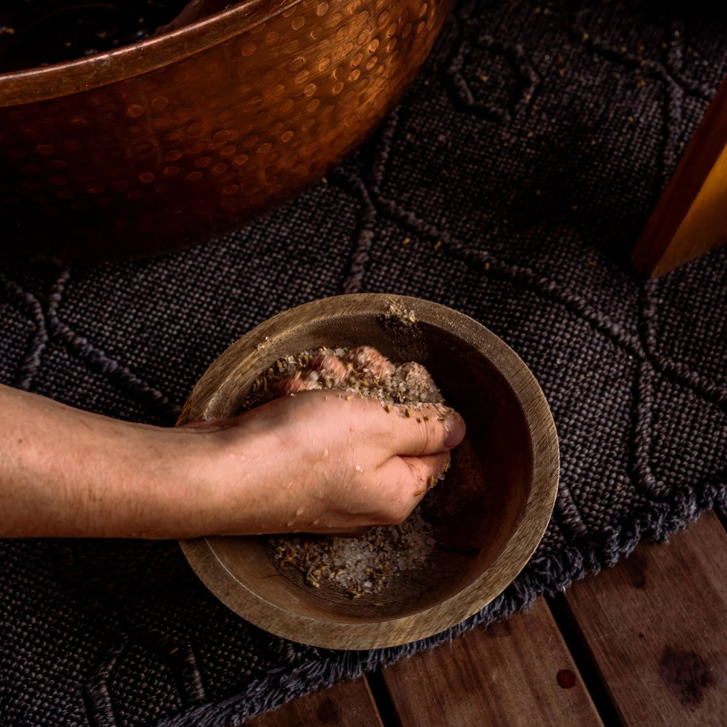 A hand reaches into a bowl of scrubbing salts used in a Knot Springs foot rub treatment