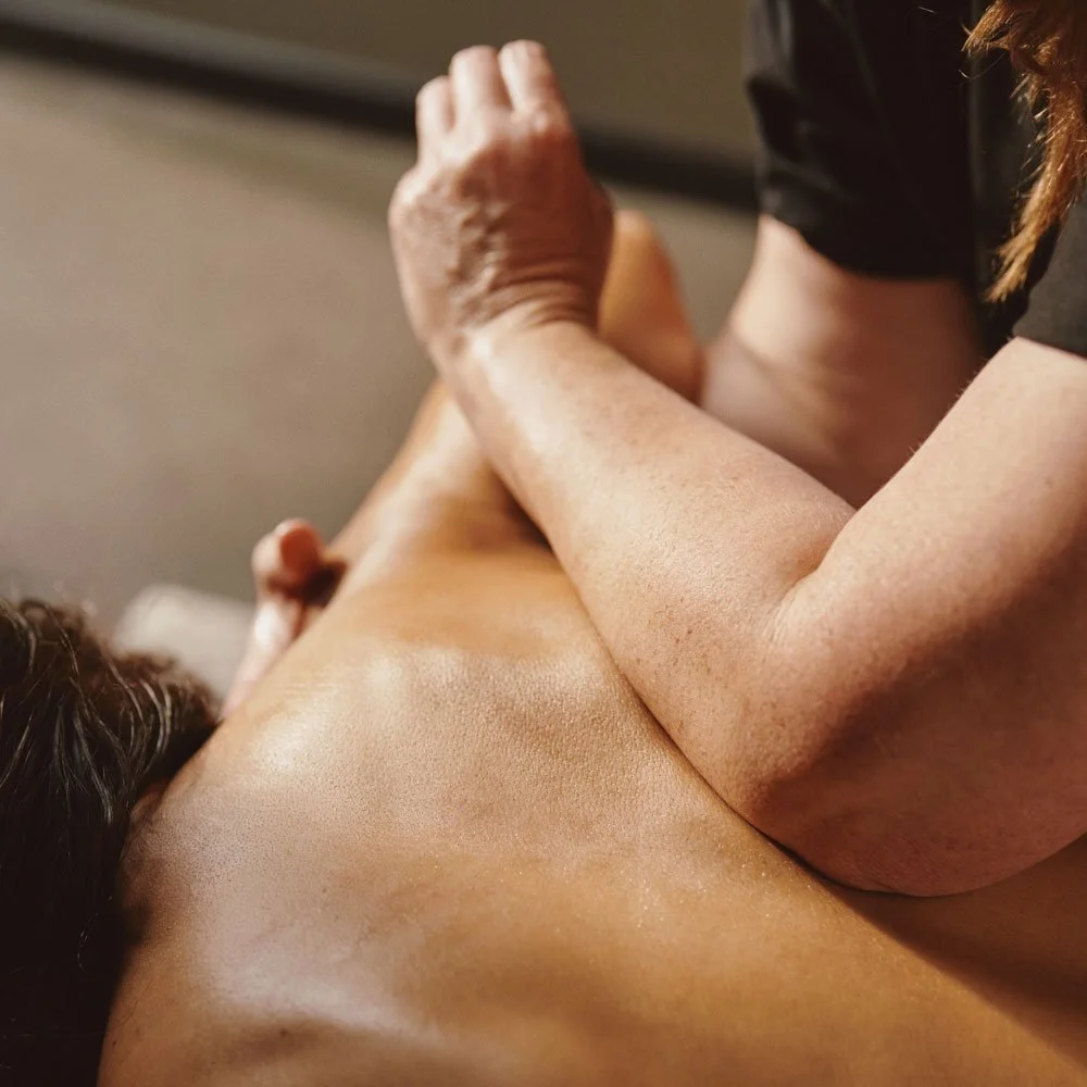 An elbow being pushed into another person's back, performing a deep tissue massage