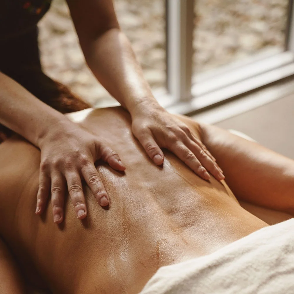 Two hands massaging a back, performing a Swedish massage