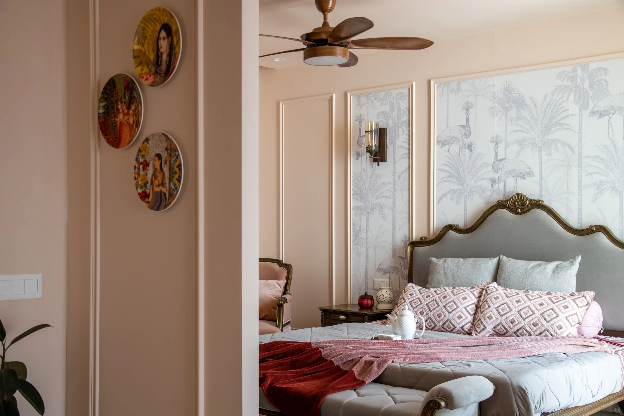 A bedroom with a large bed, decorative pillows, a wooden nightstand, and tropical-themed wallpaper featuring palm trees and exotic animals.