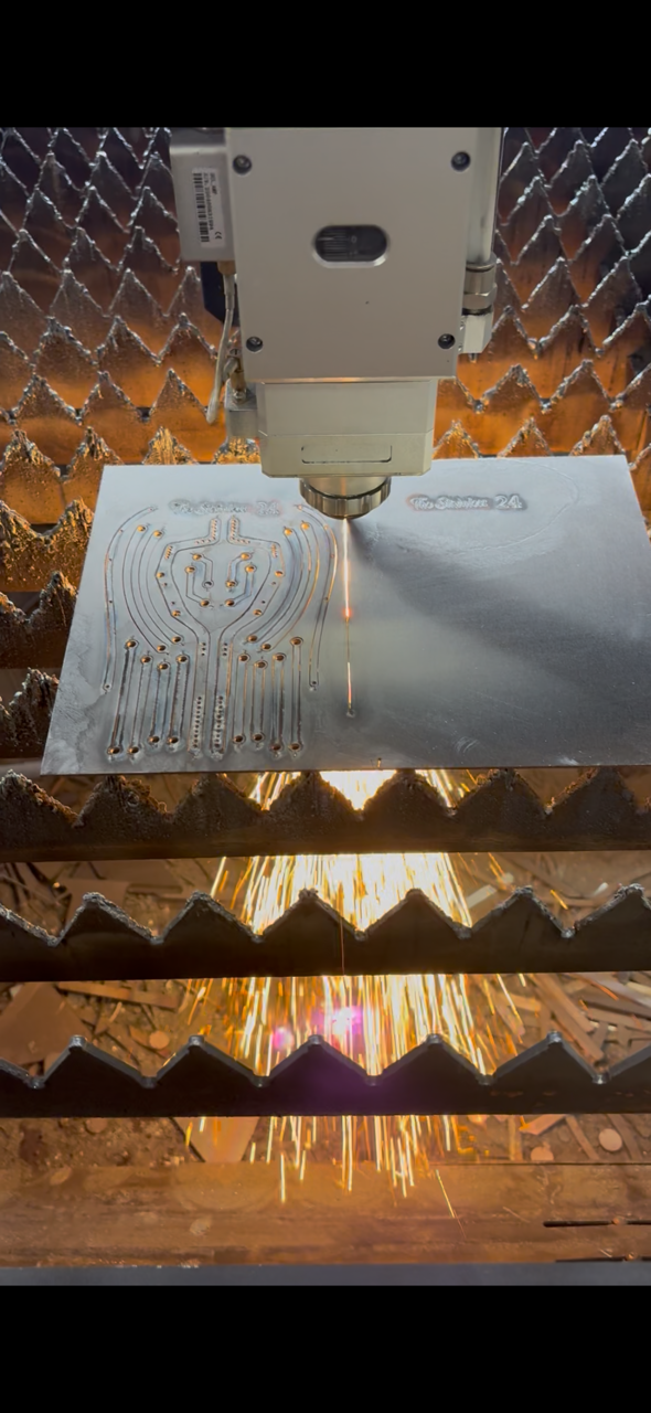 A laser cutter engraving a circuit board with sparks flying from the cutting process.