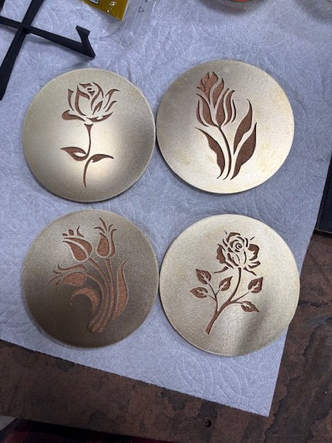 Four circular plates with floral designs cut out from the center, placed on a table.