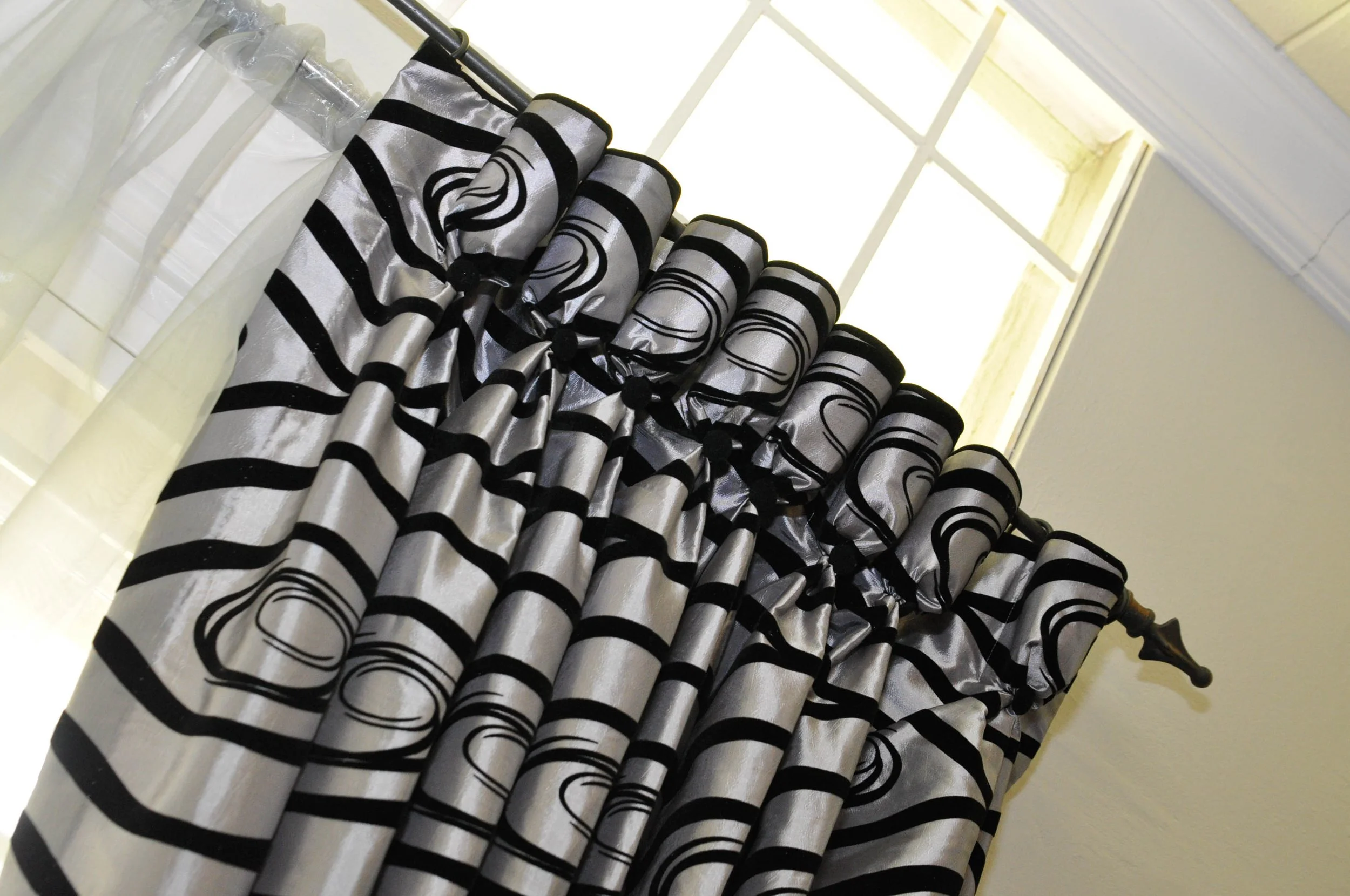 Black and silver striped curtains hanging on a rod in front of a window.