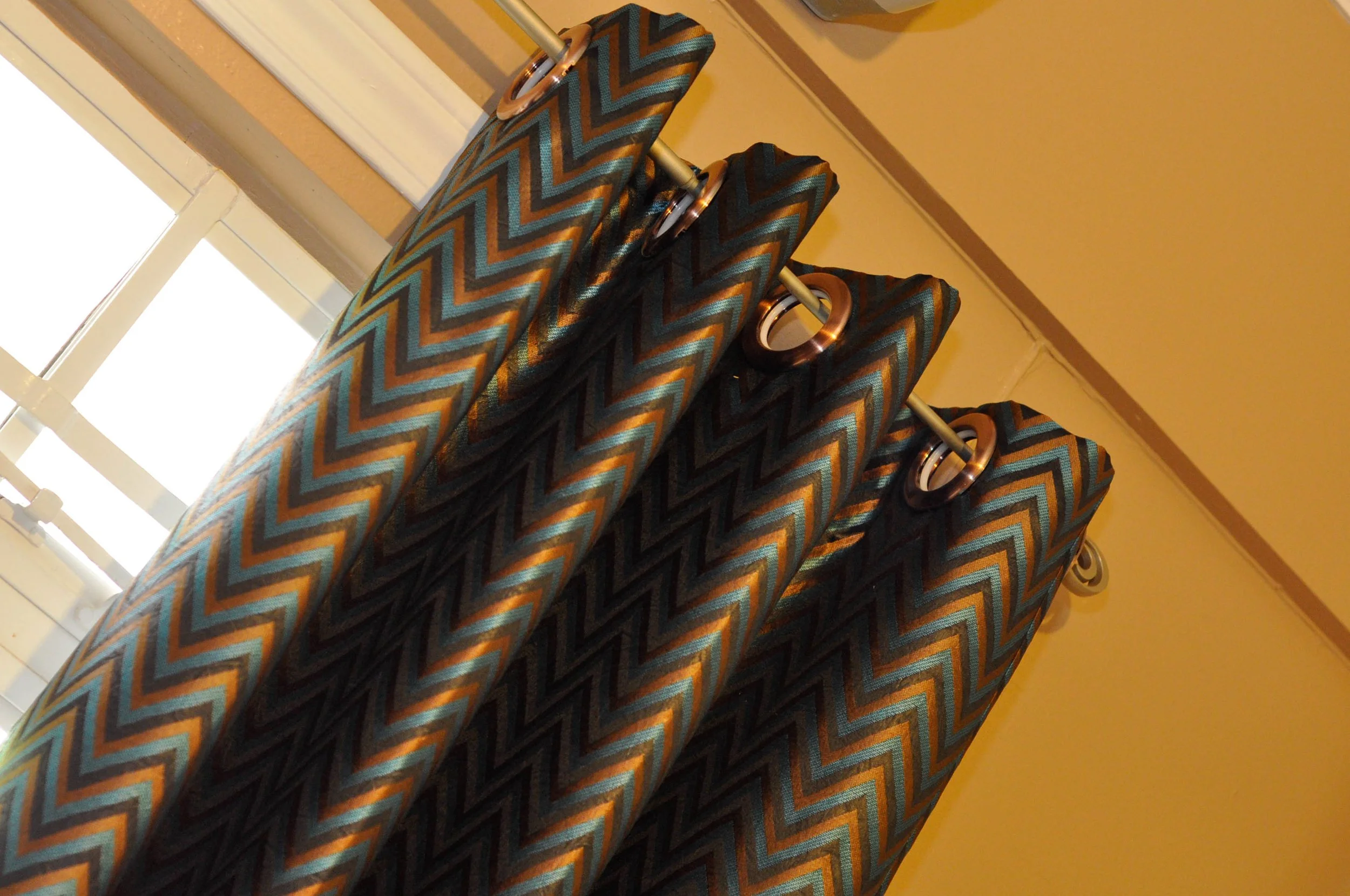 Colorful patterned curtains hanging from a curtain rod near a window.