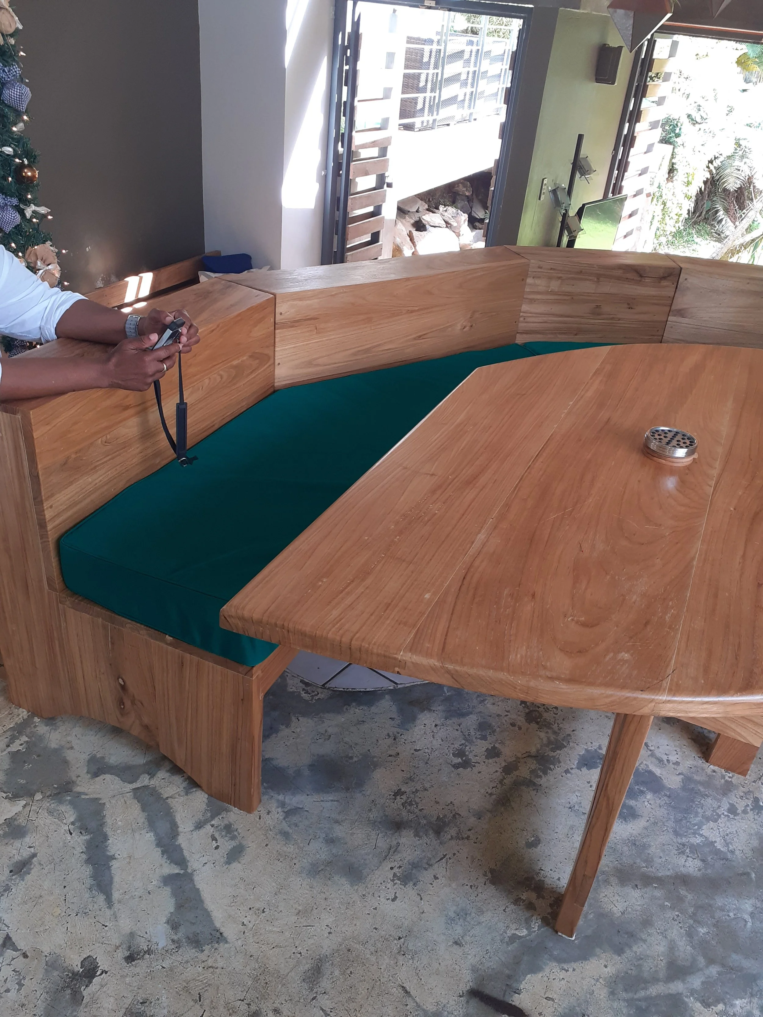 Wooden booth with green cushion seating at a dining table in a modern indoor space with natural light.