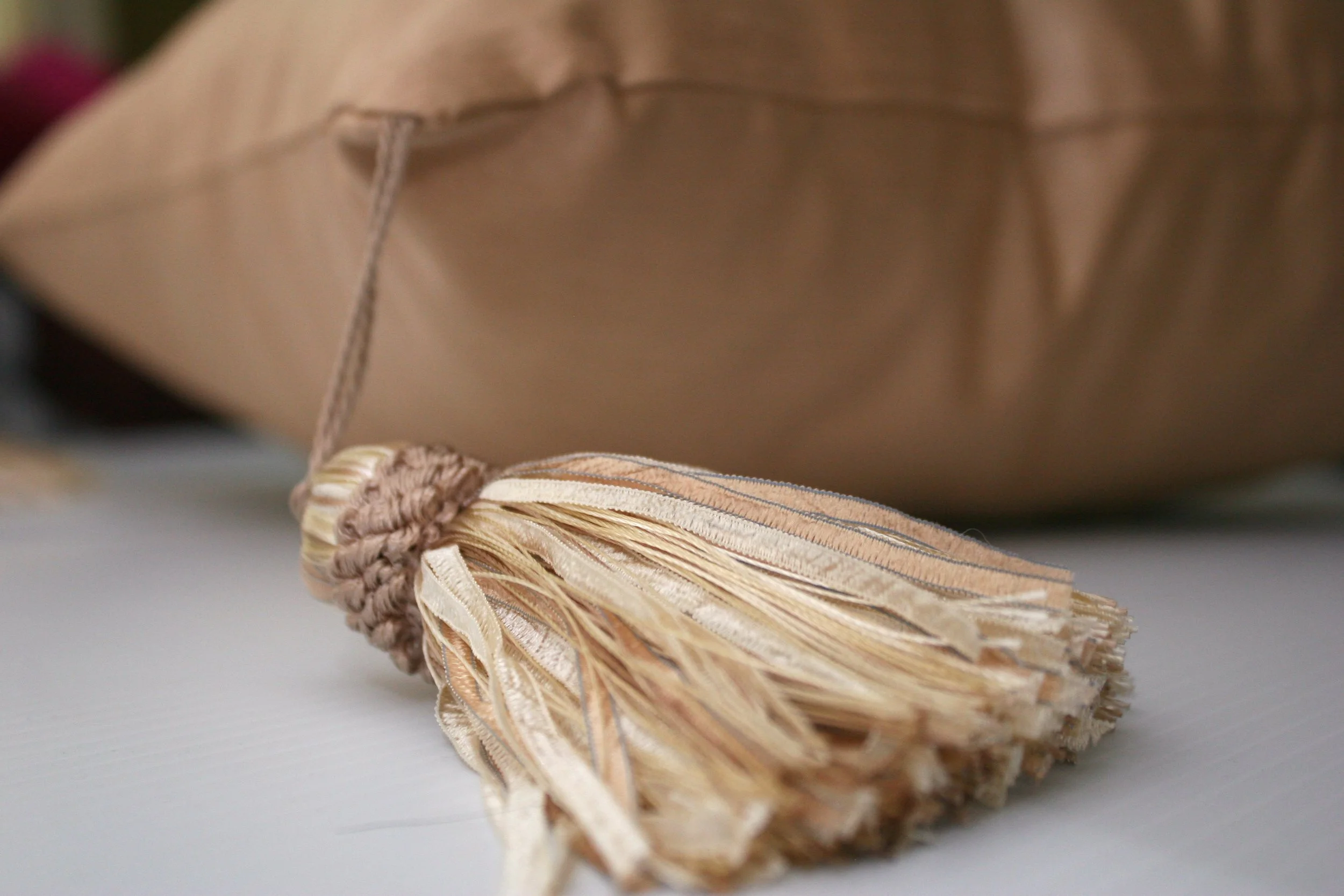 A beige graduation cap with a gold tassel lying on a white surface.
