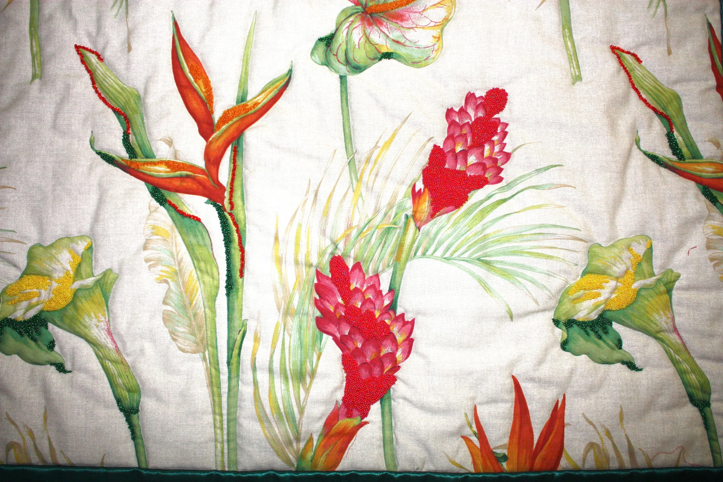 Fabric with embroidered tropical flowers, including red ginger and calla lilies, with green and yellow leaves.