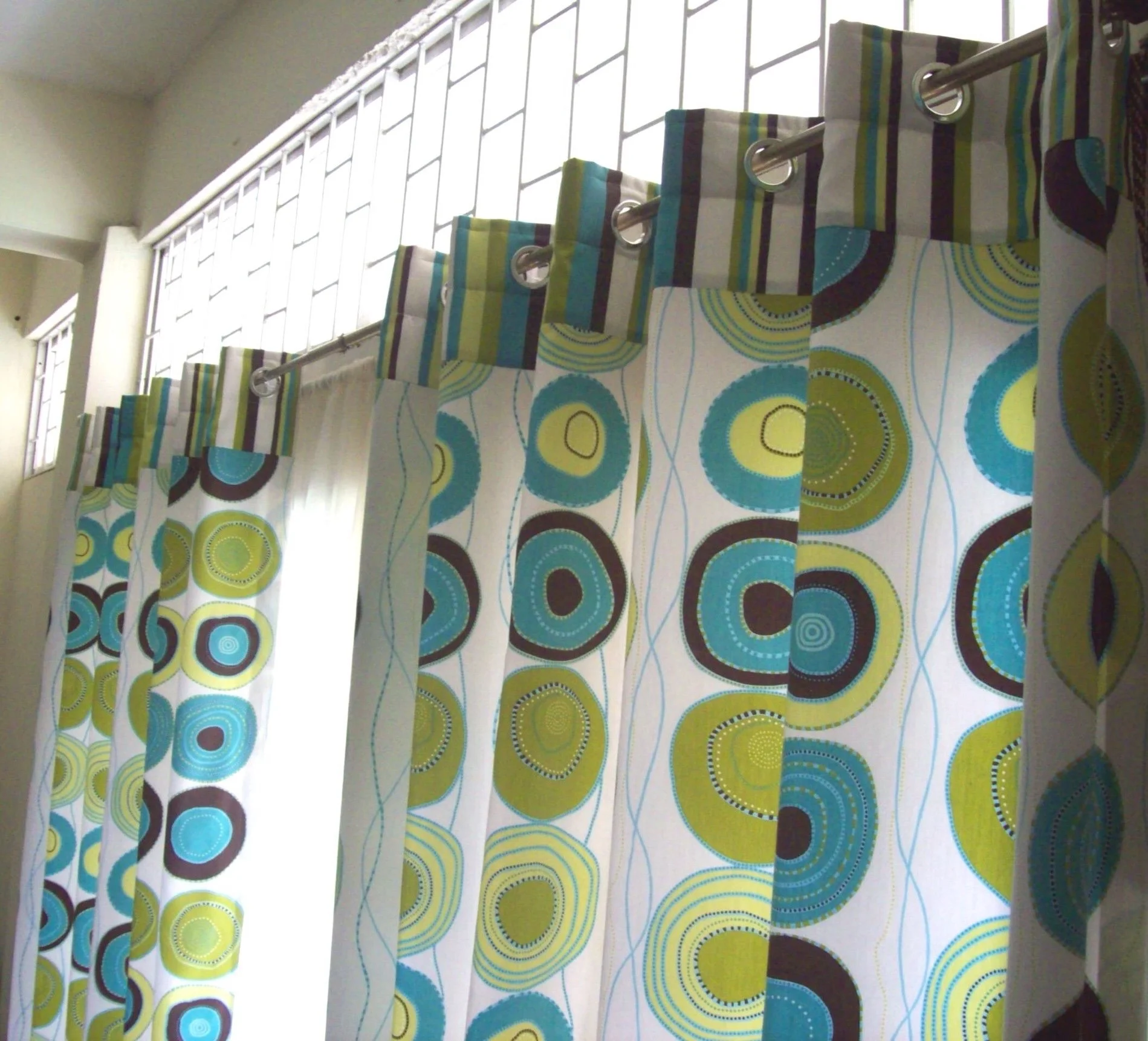 Decorative curtains with a colorful circular and striped pattern on a window.