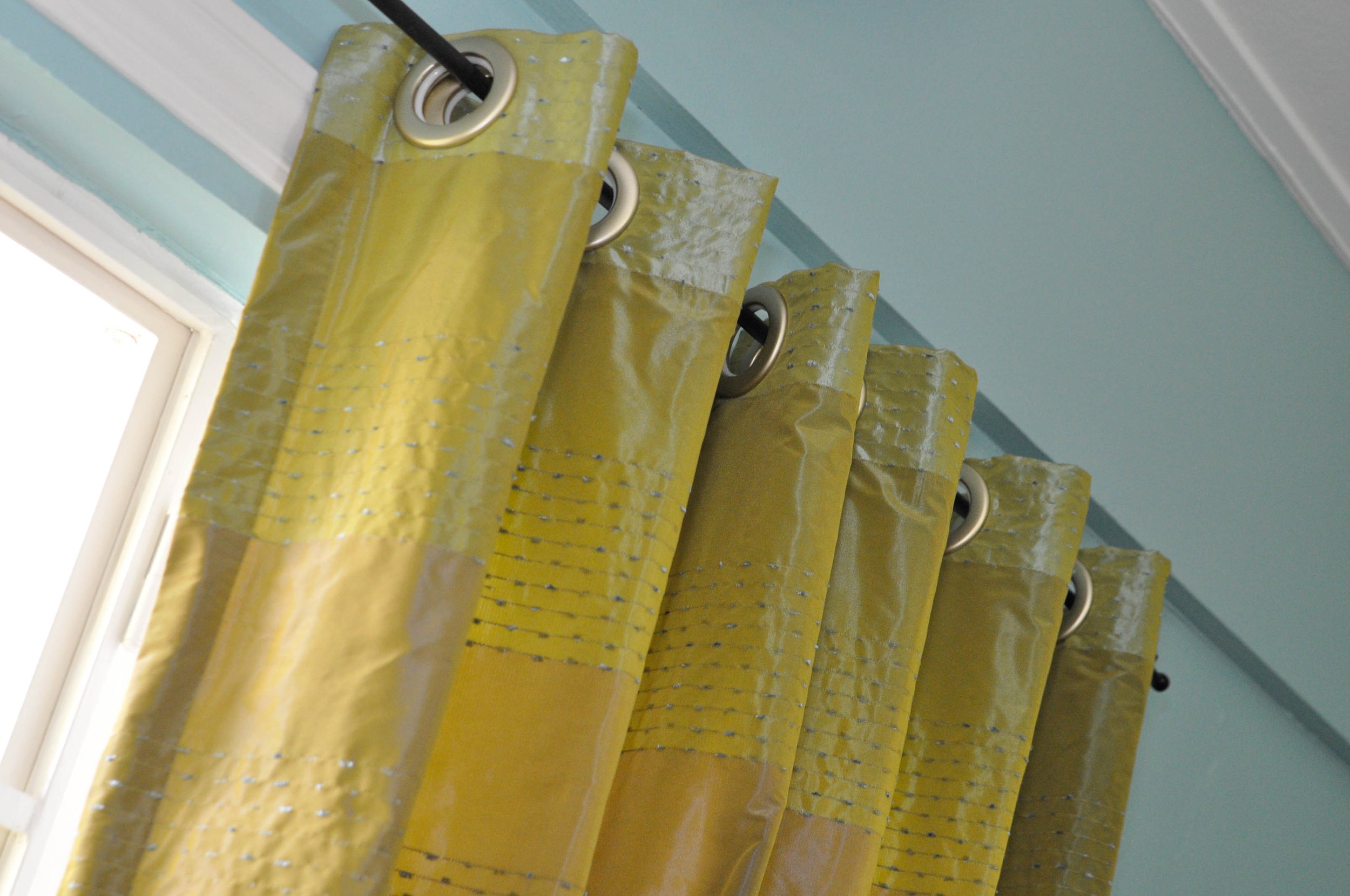 Yellow insulated curtains hanging near a window in a room with blue walls.