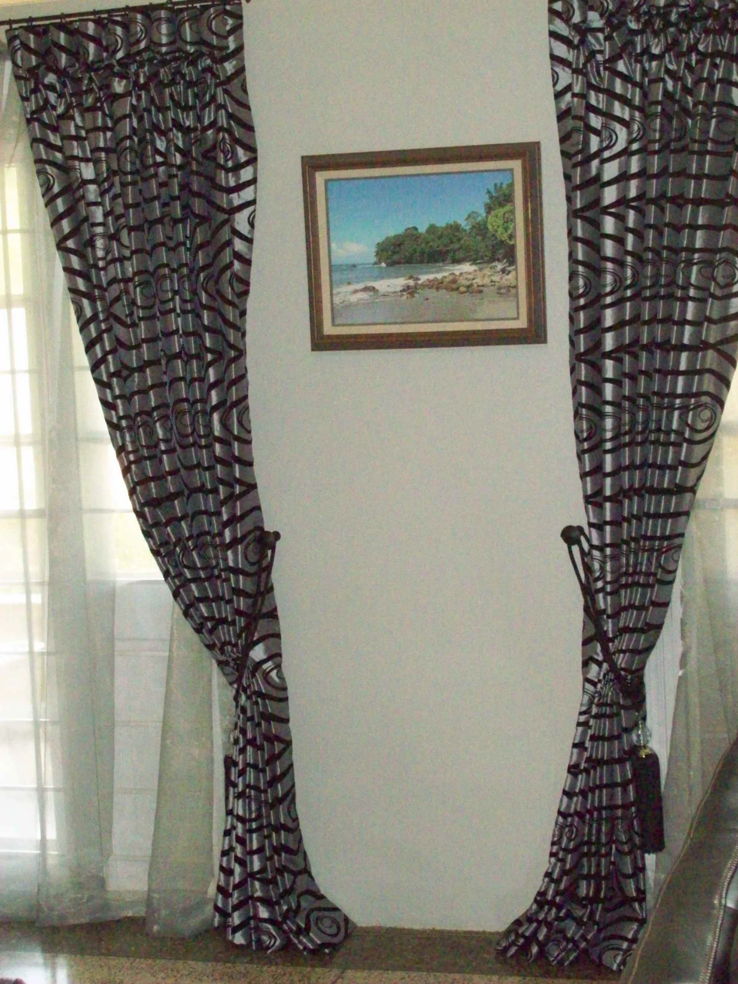 Curtains framing a doorway with a landscape painting on the wall behind.