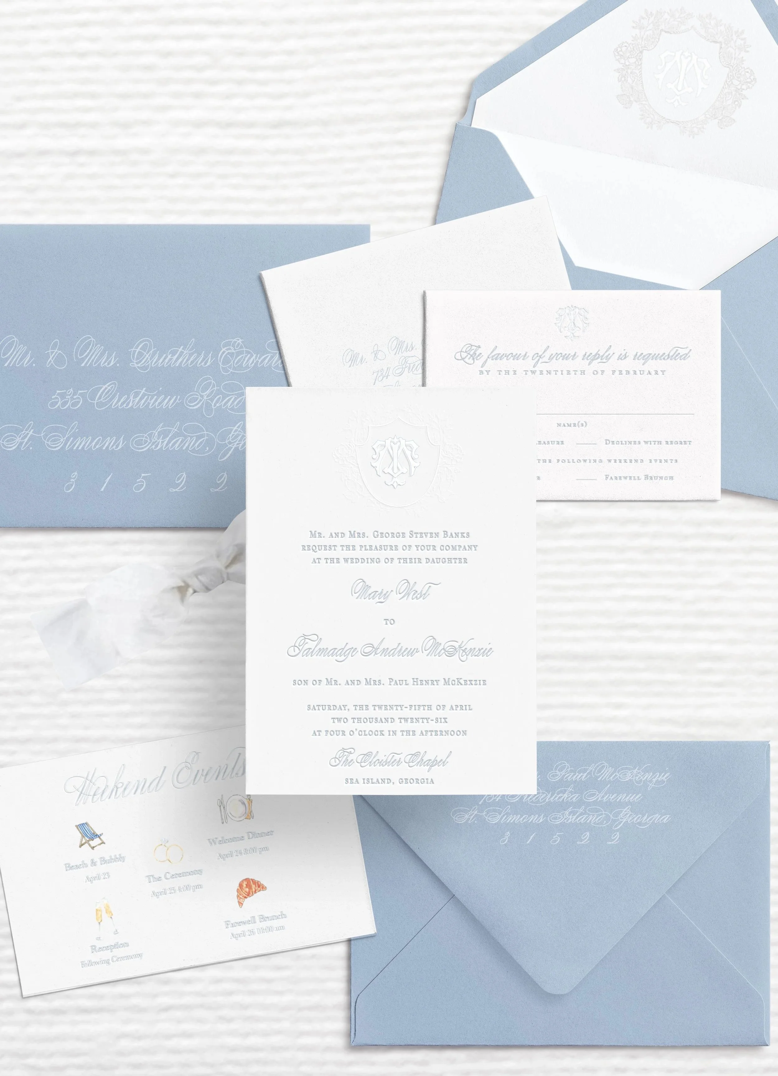 Custom invitation suite featuring calm coastal blues with a subtle monogram and crest, rsvp card, wedding details, and envelope liners.