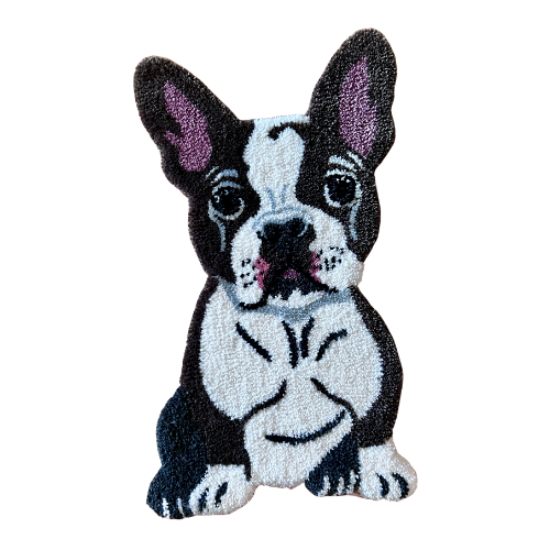 A plush rug in the shape of a French Bulldog puppy with large eyes and a black and white coat.