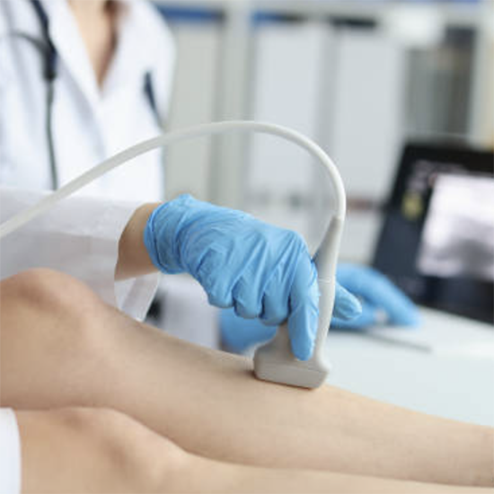 A healthcare professional wearing blue gloves performing an ultrasound on a patient's arm in a medical setting.