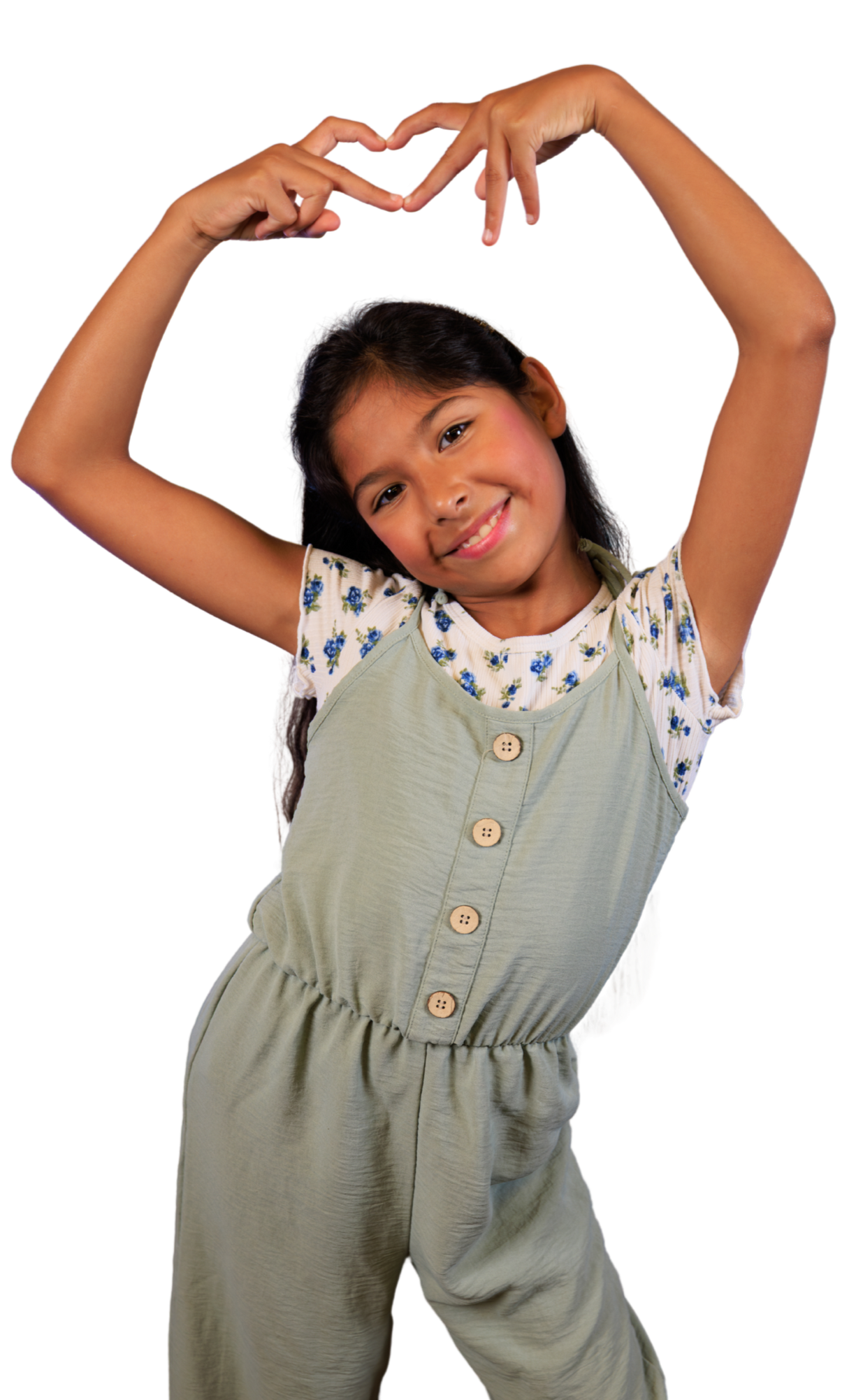 A young girl with long dark hair smiling and forming a heart shape with her hands above her head.
