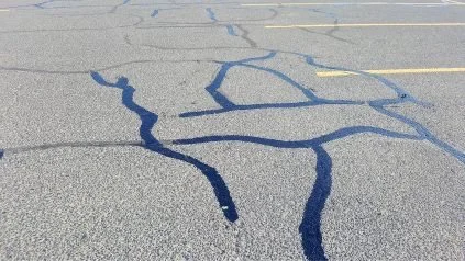 Cracks and dark oil stains on the asphalt road surface.