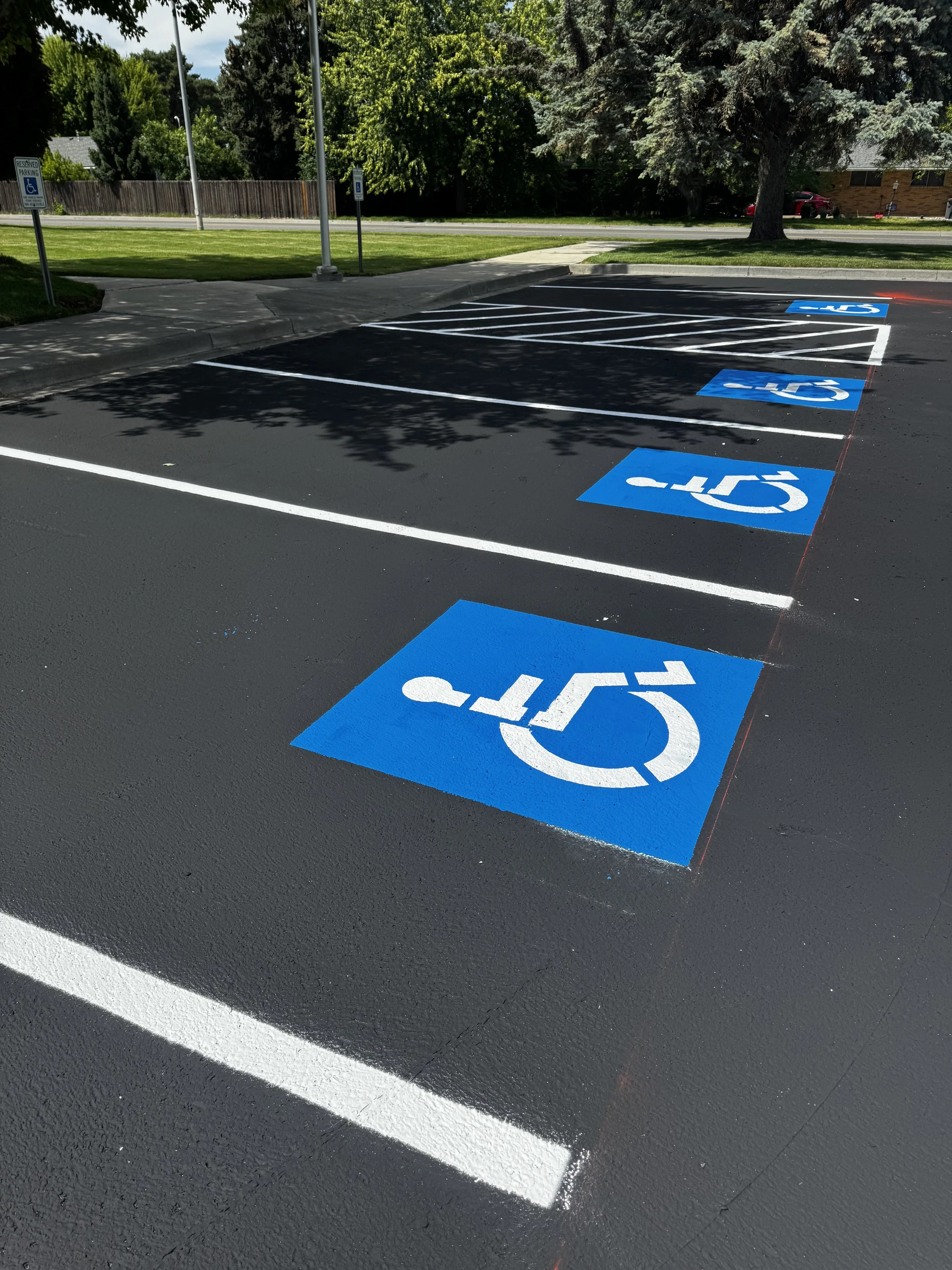Parking lot with designated accessible parking spaces marked with blue signs and symbols painted on the ground.