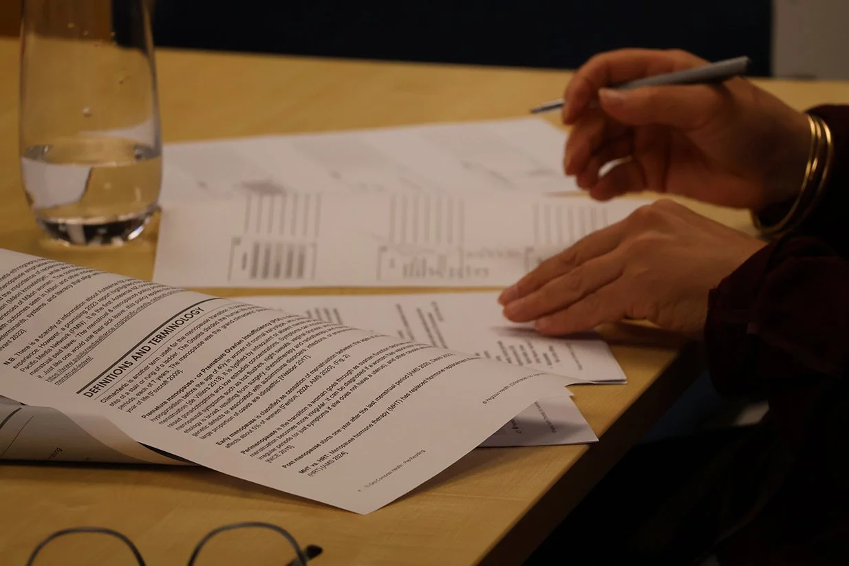 Person reviewing and writing on documents with a glass of water on the table.