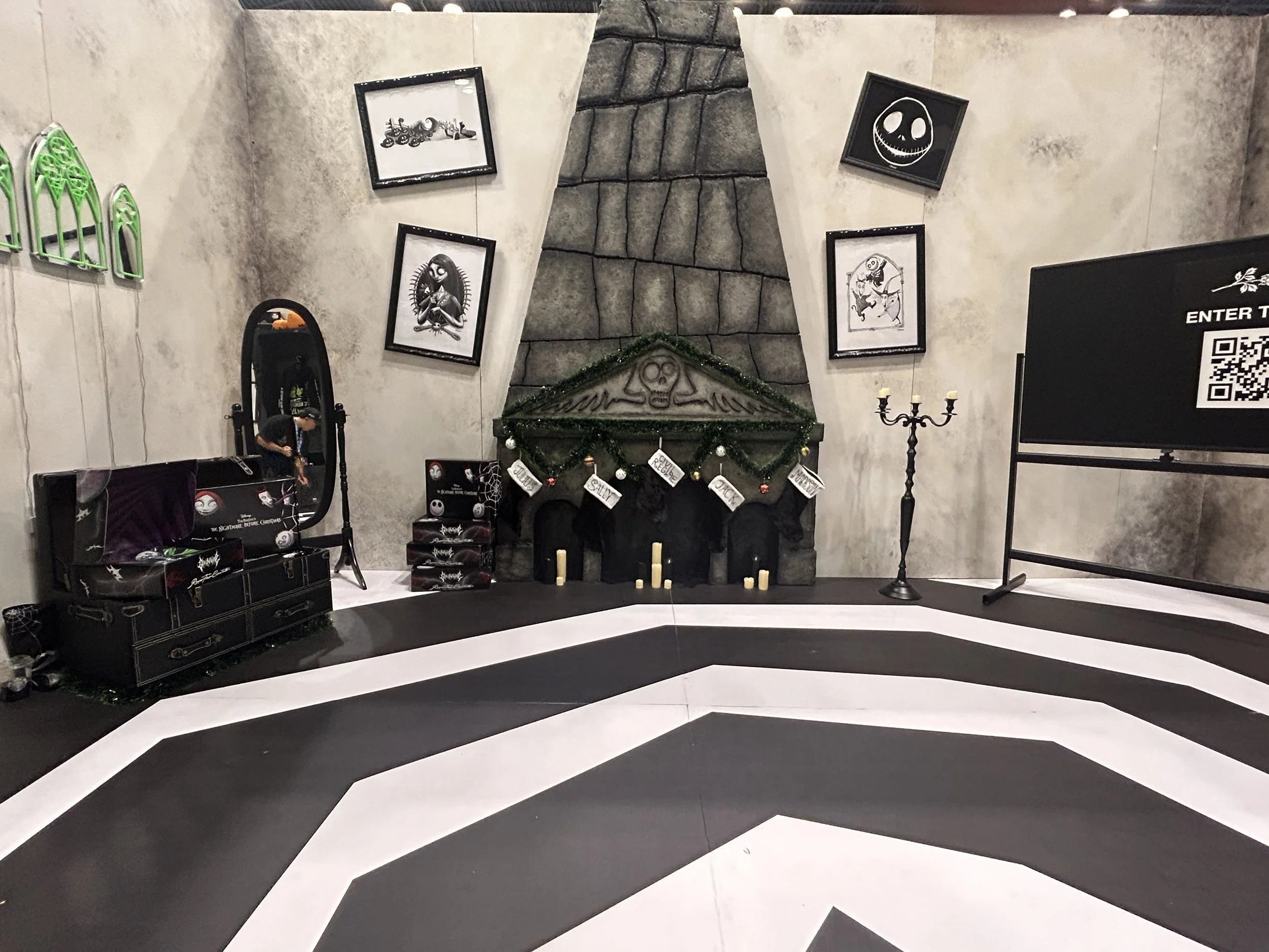 New York Comic Con 2024 Nightmare Before Christmas event activation for the clothing brand.A decorated halloween-themed room with a black and white striped floor, a stone fireplace with candles and a green garland, framed spooky artwork on the walls.