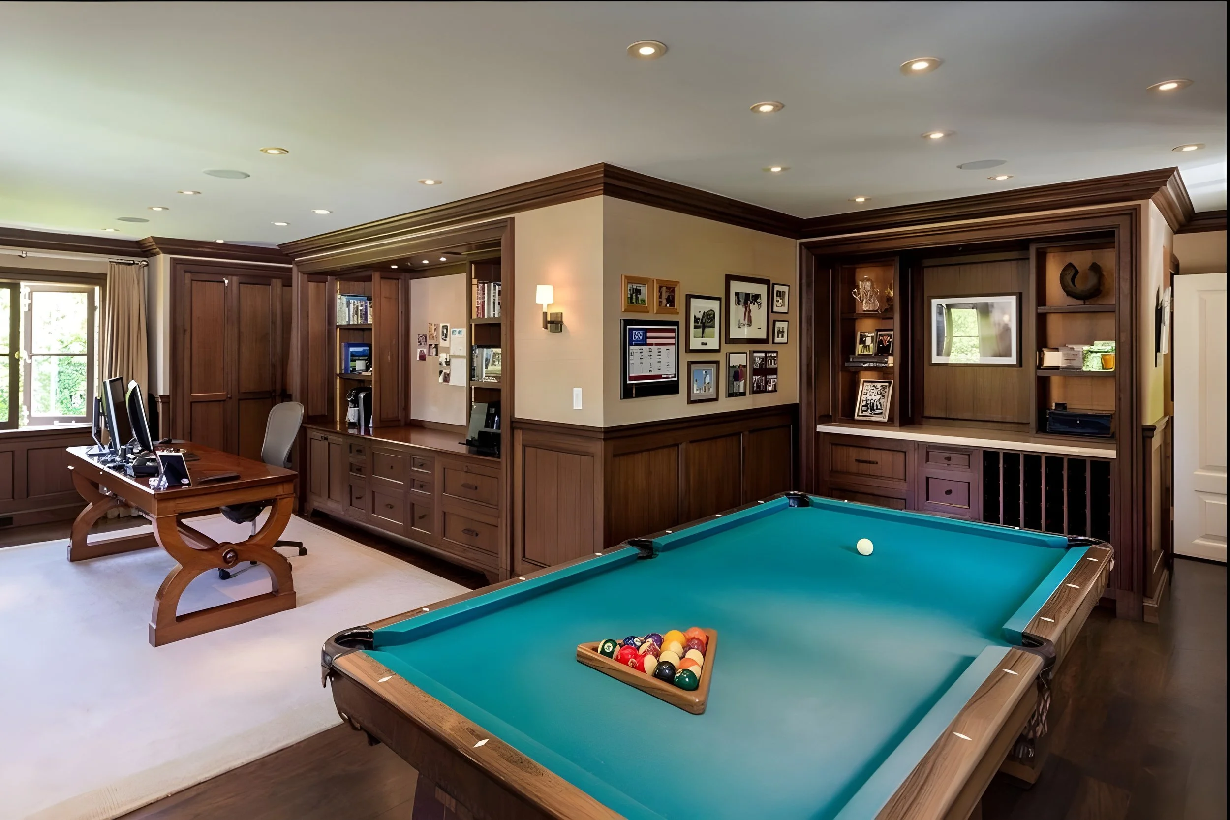 Home office with pool table, computer desk, and built-in wooden shelves and cabinets.