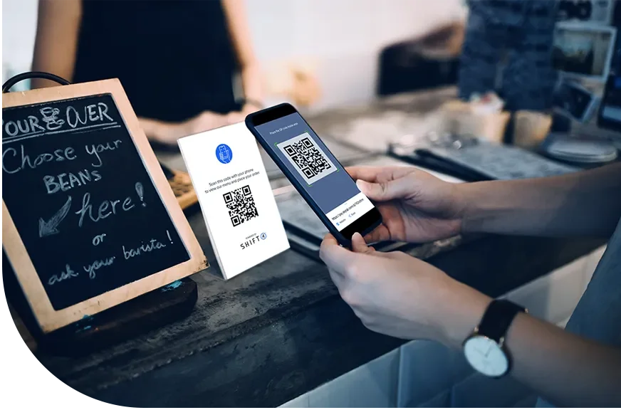 Person scanning a QR code on a phone at a coffee shop or cafe counter.