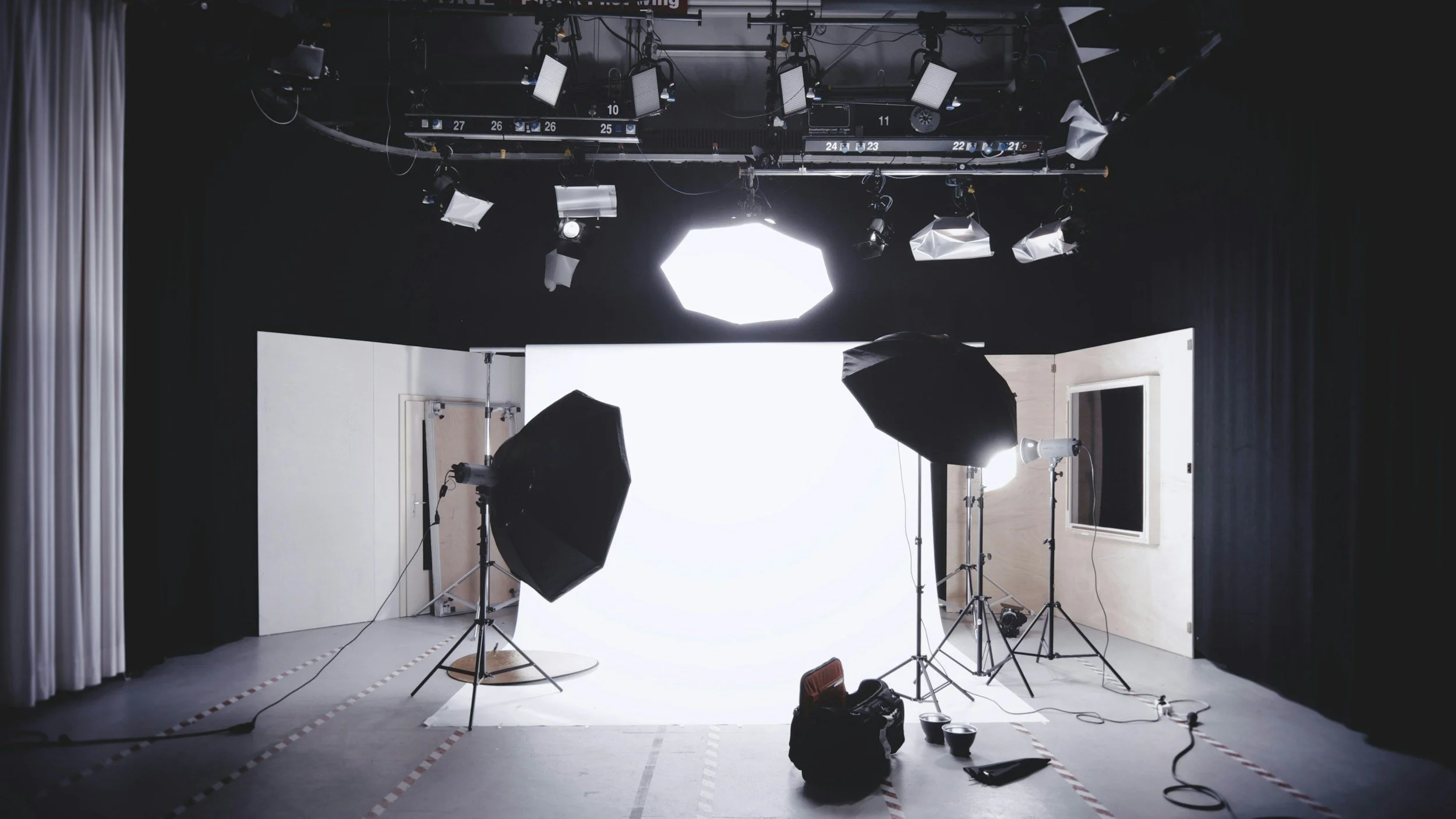 Photography studio with lighting equipment, softboxes, and a white backdrop.