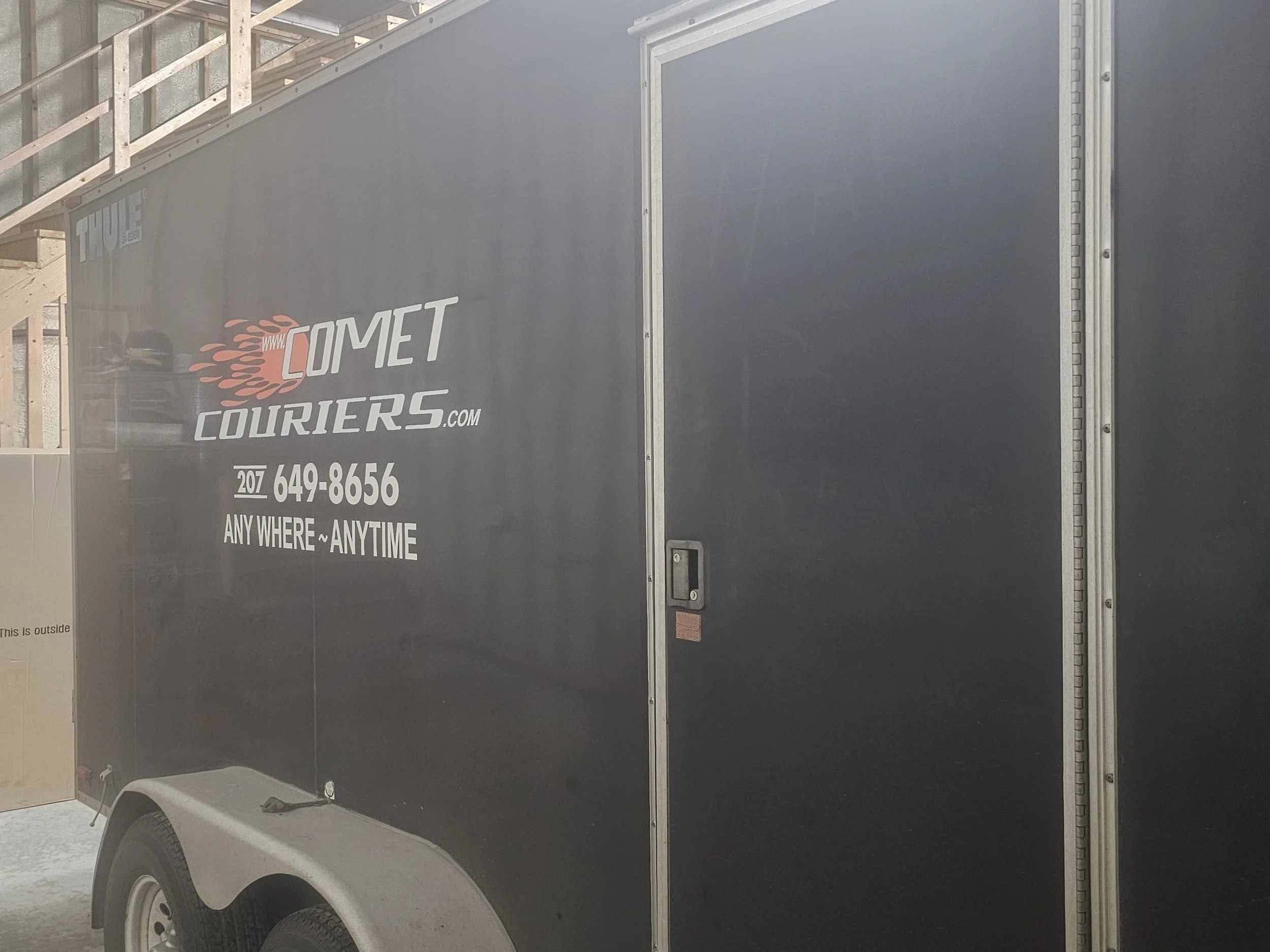 Black enclosed trailer with Comet Couriers logo
