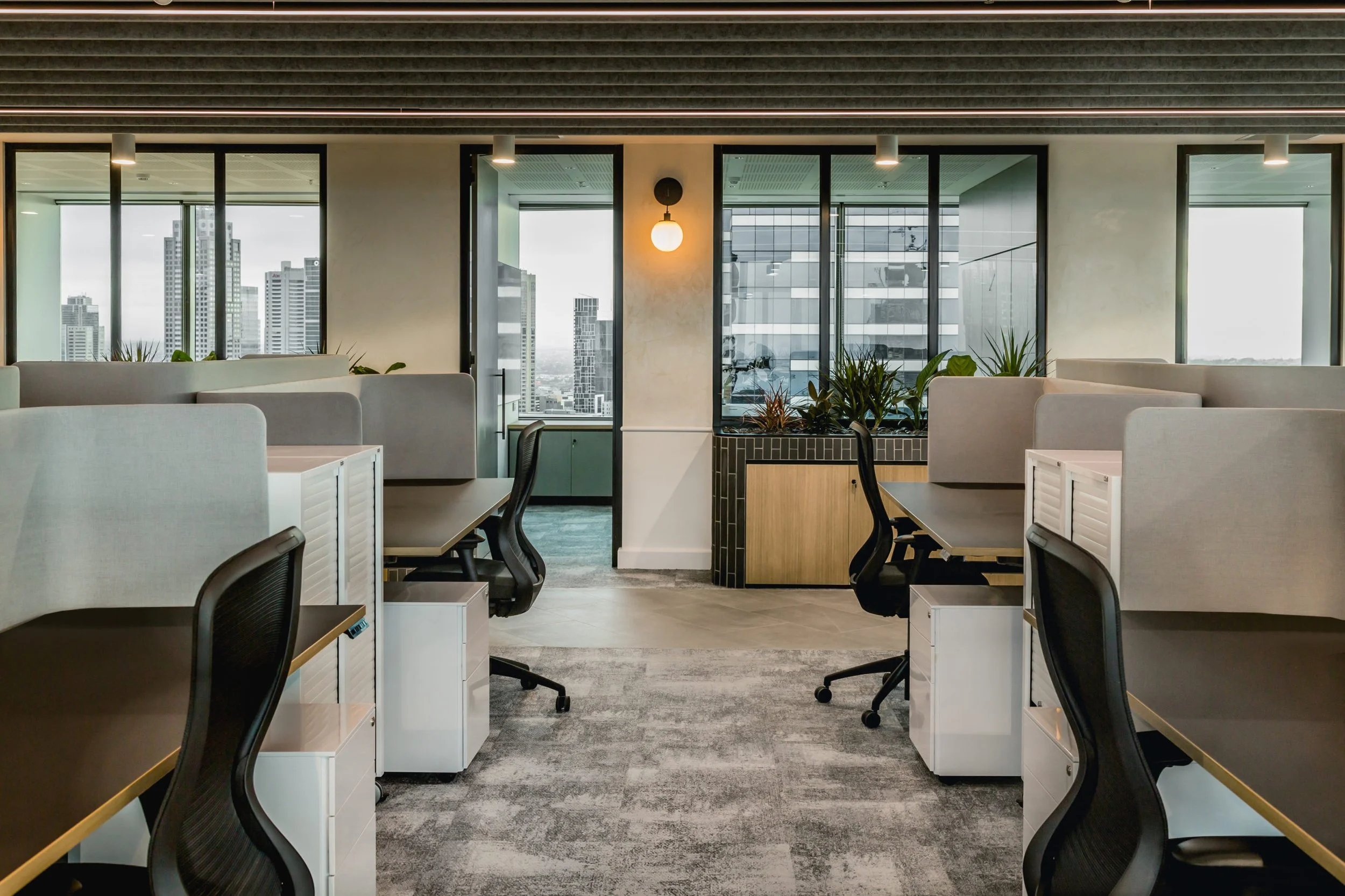 Modern office with desks, chairs, large windows, and city skyline view
