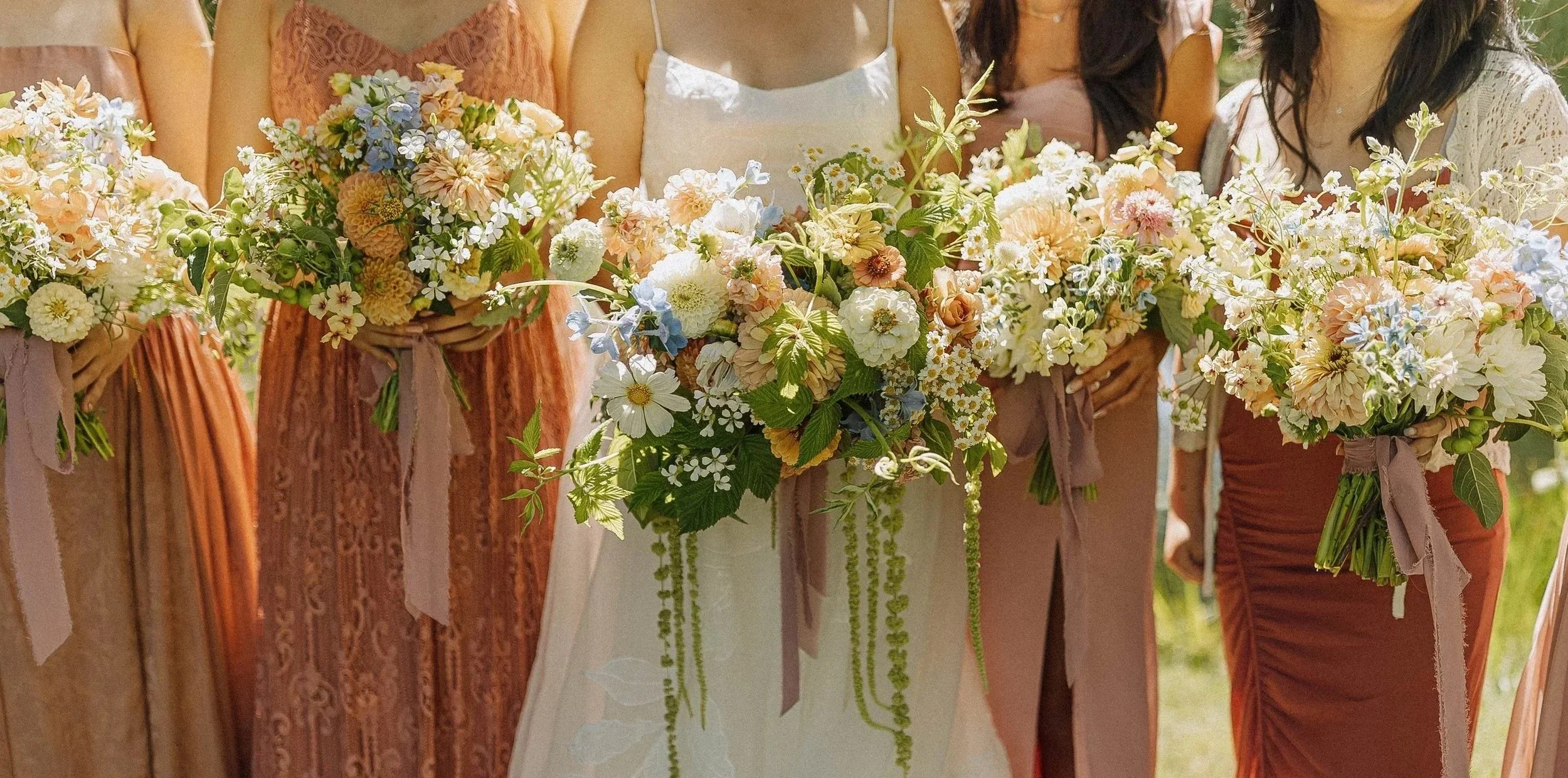 Laurie’s customers, Mariana and Carmen holding hands on a green lawn on their wedding day.