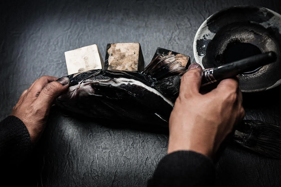 Gyotaku artist Dwight Hwang applies ink to a fish after supporting it for printing.