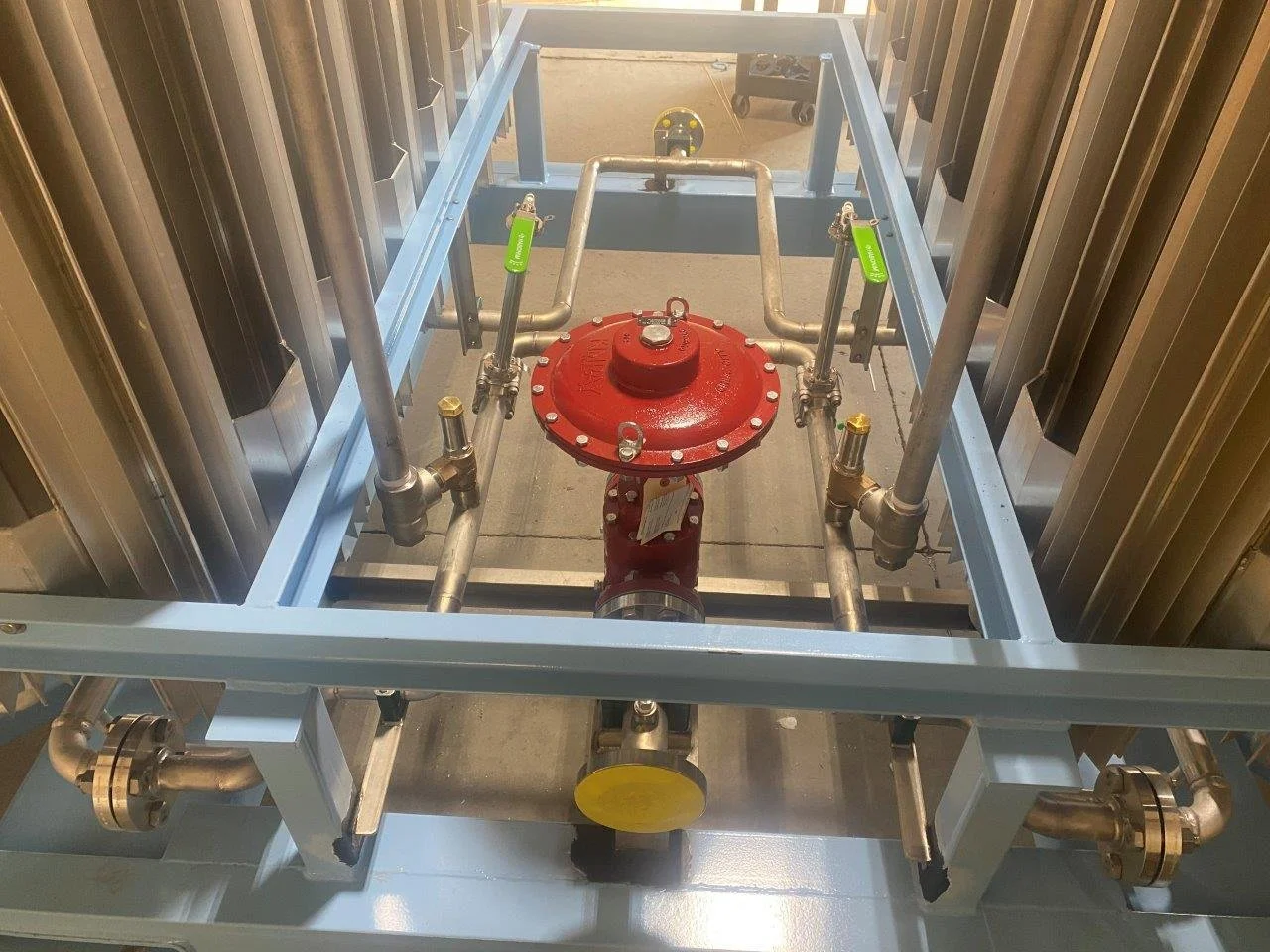 Industrial pipe system with a red valve and metal framework.
