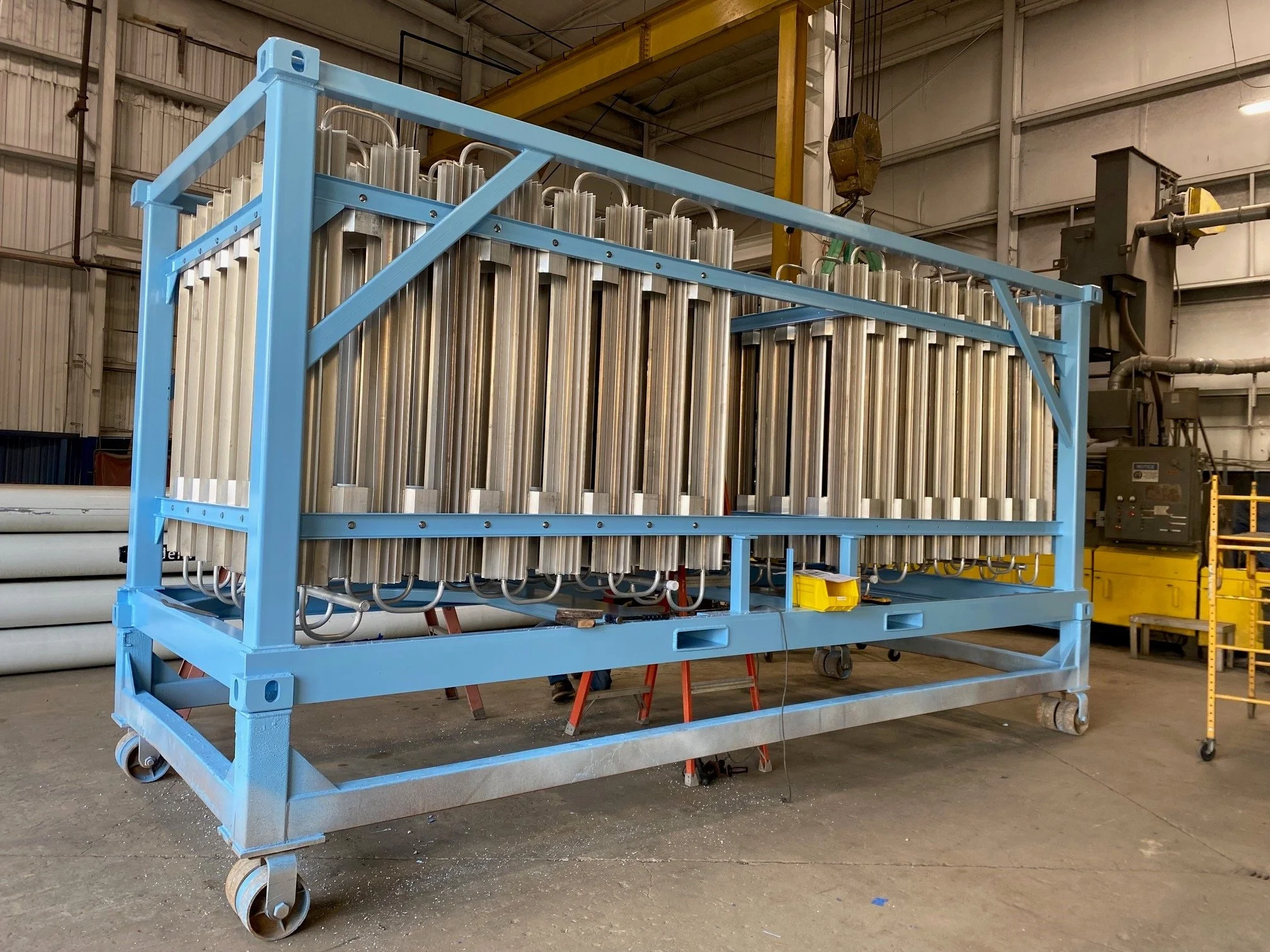 Large industrial frame with multiple metal cylinders and pipes inside a warehouse or factory setting.