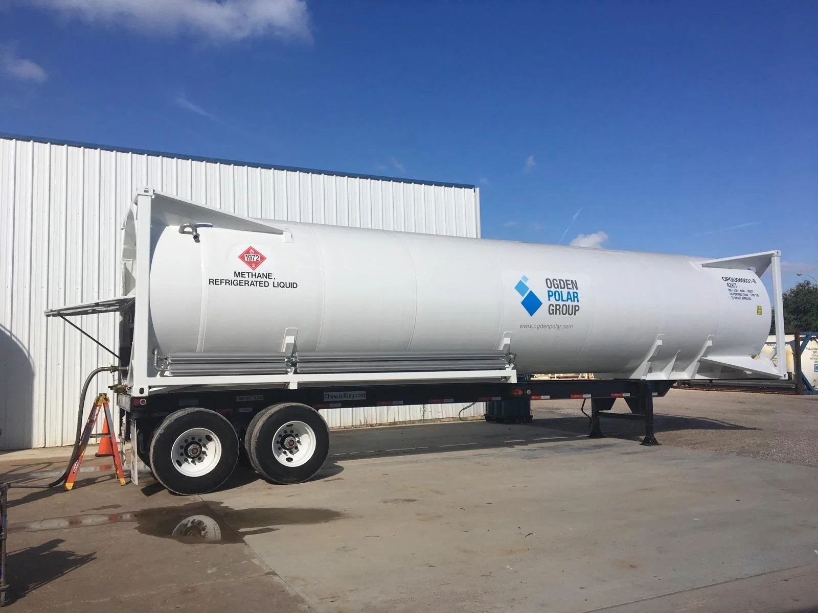 Fuel tanker truck with Ogden Polar Group logo, labeled for refrigerated liquid methane, parked outside near a white building under a blue sky.