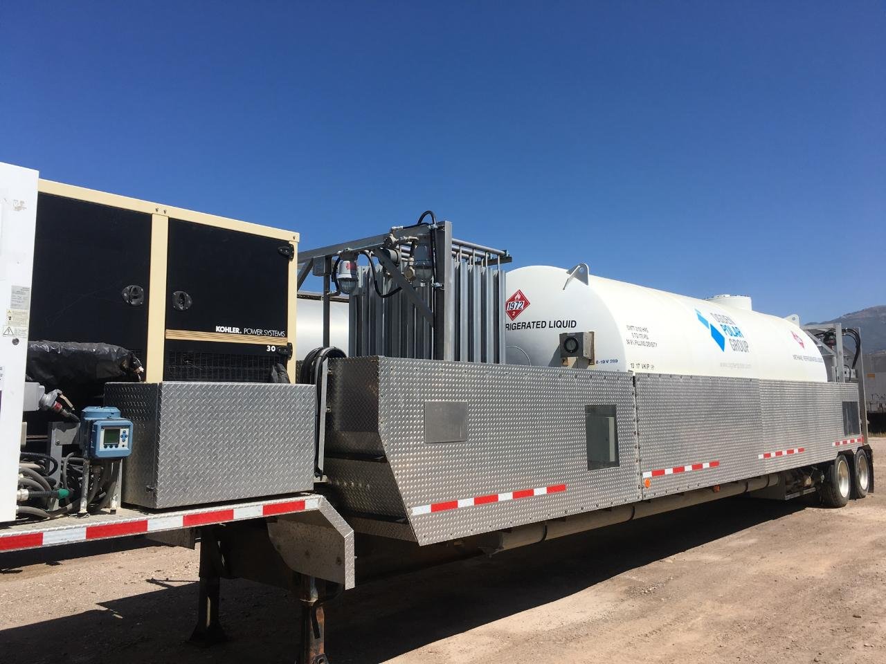 A large mobile fuel tanker truck with a white tank labeled 'Refrigerated Liquid' and 'Kohler Power Systems' generator on a clear day with blue sky.