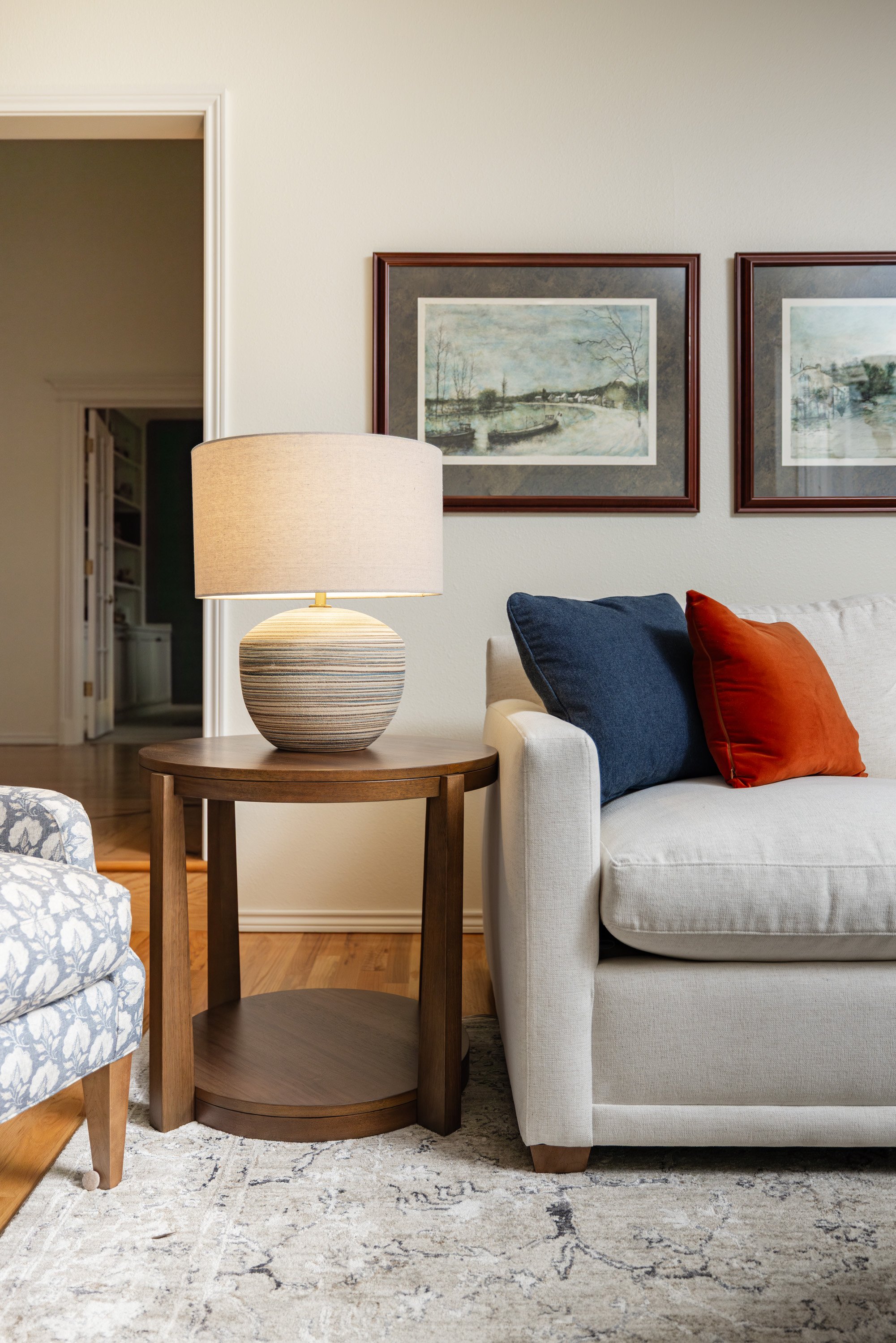 white loveseat, blue and orange accent pillows, blue lamp white loveseat and a peak at a blue floral accent chair