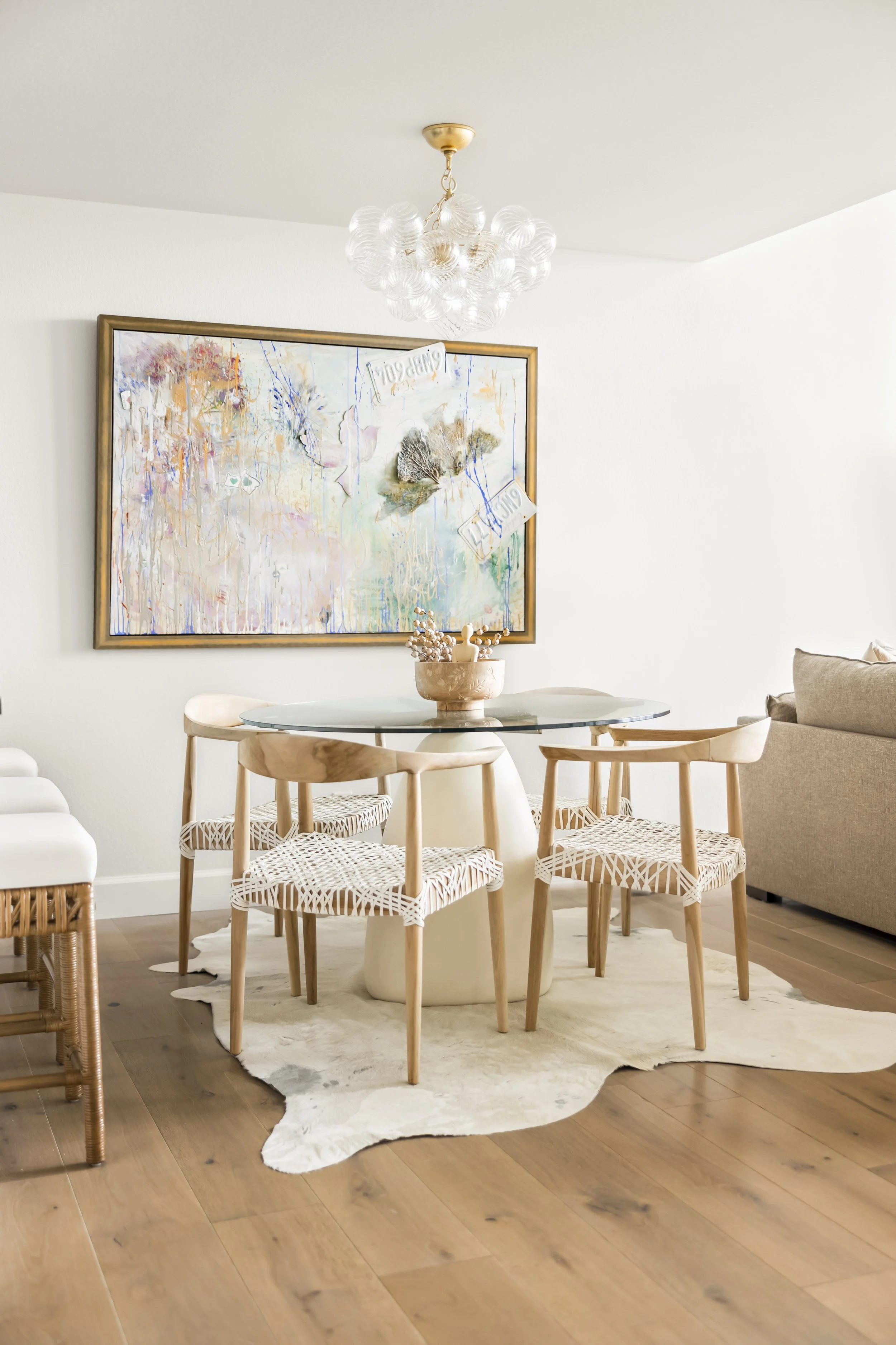 Dining area with round glass pedestal table and woven chairs, Vancouver WA condo interior design by Design With Refinement
