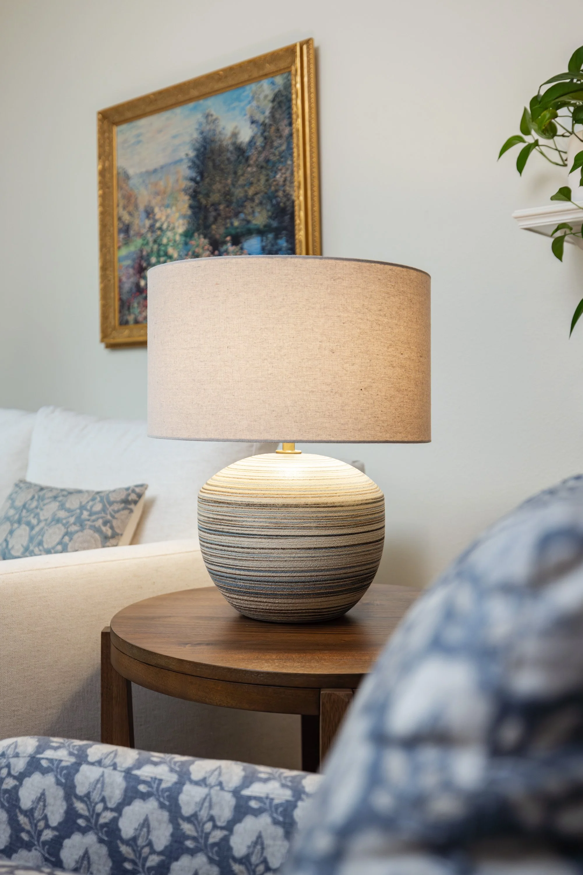 Traditional landscape art, blue lamp white loveseat and a peak at a blue floral accent chair