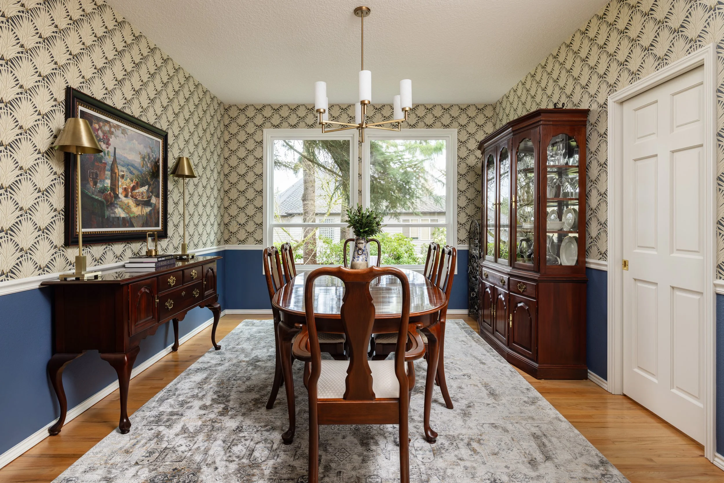 Traditional dining table with updated lighting and silver rug, blue paint and wallpaper