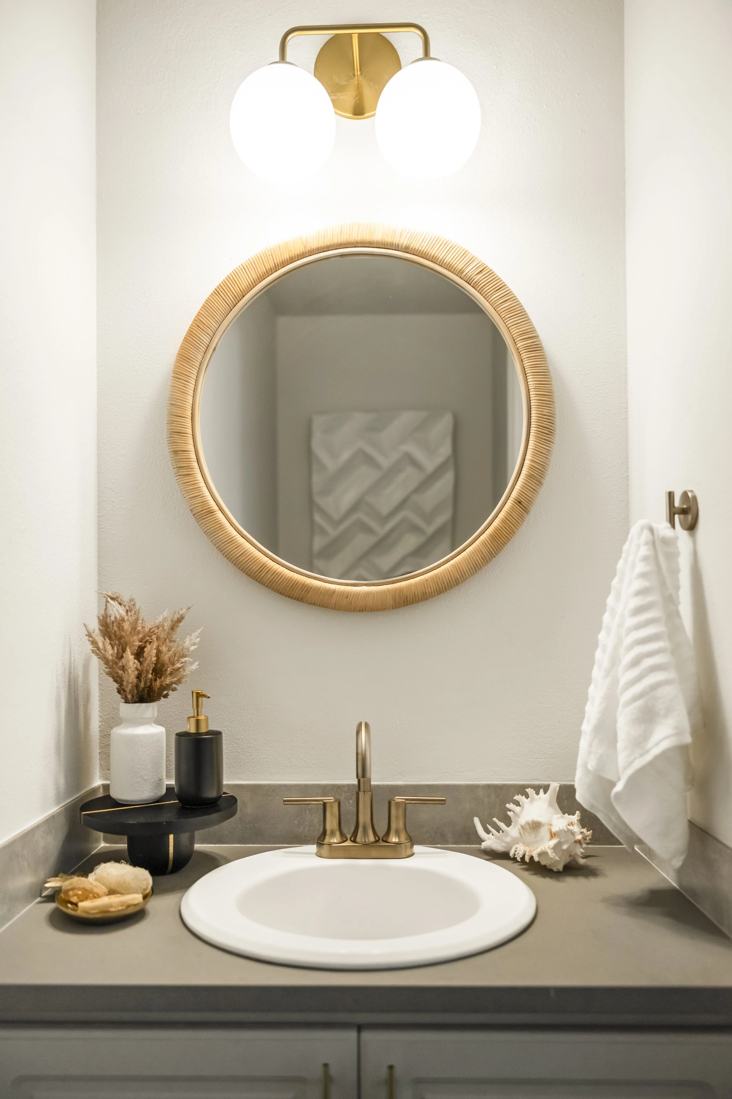 Powder room with woven mirror and brass sconce, Vancouver WA waterfront condo interior design