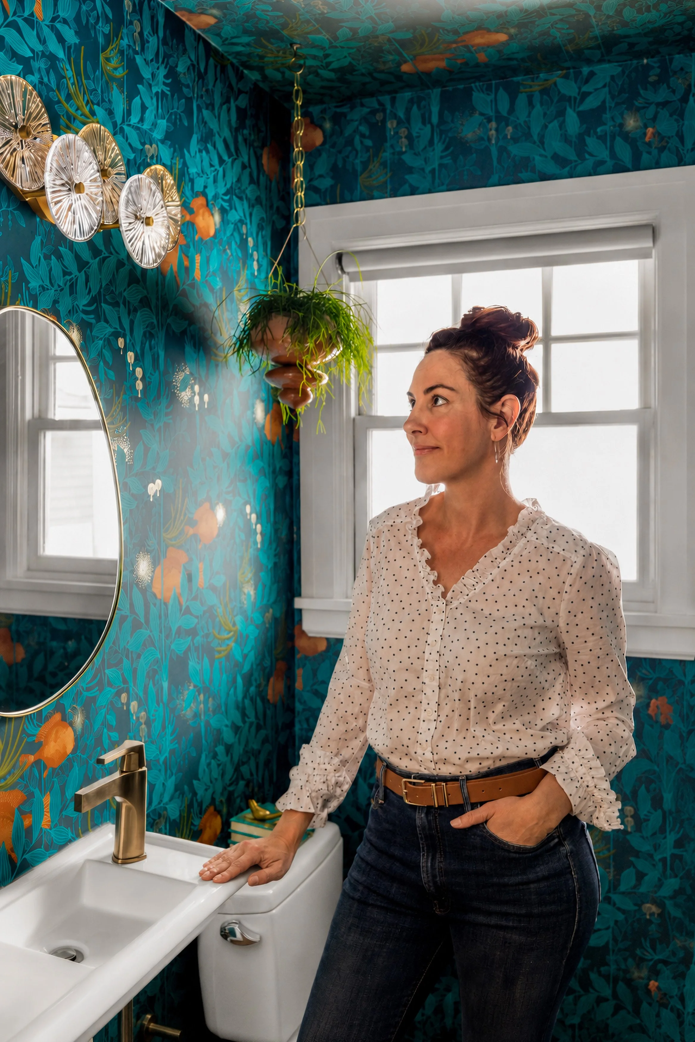 Portland interior designer Refinement Wagner looking up at the Sue-Anne vanity light in the Alameda powder room