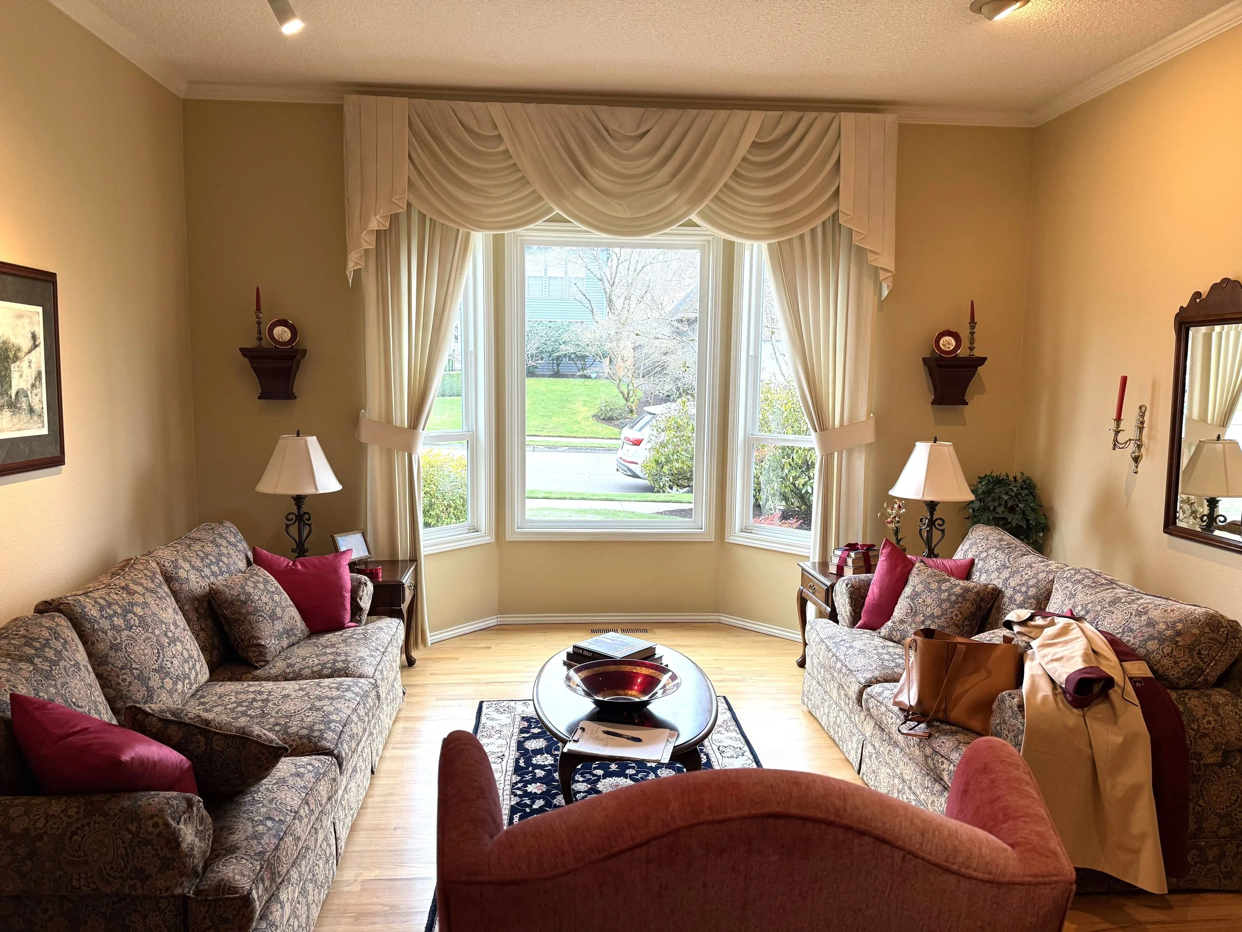 Sitting room with drapery and two floral loveseats and accents in red